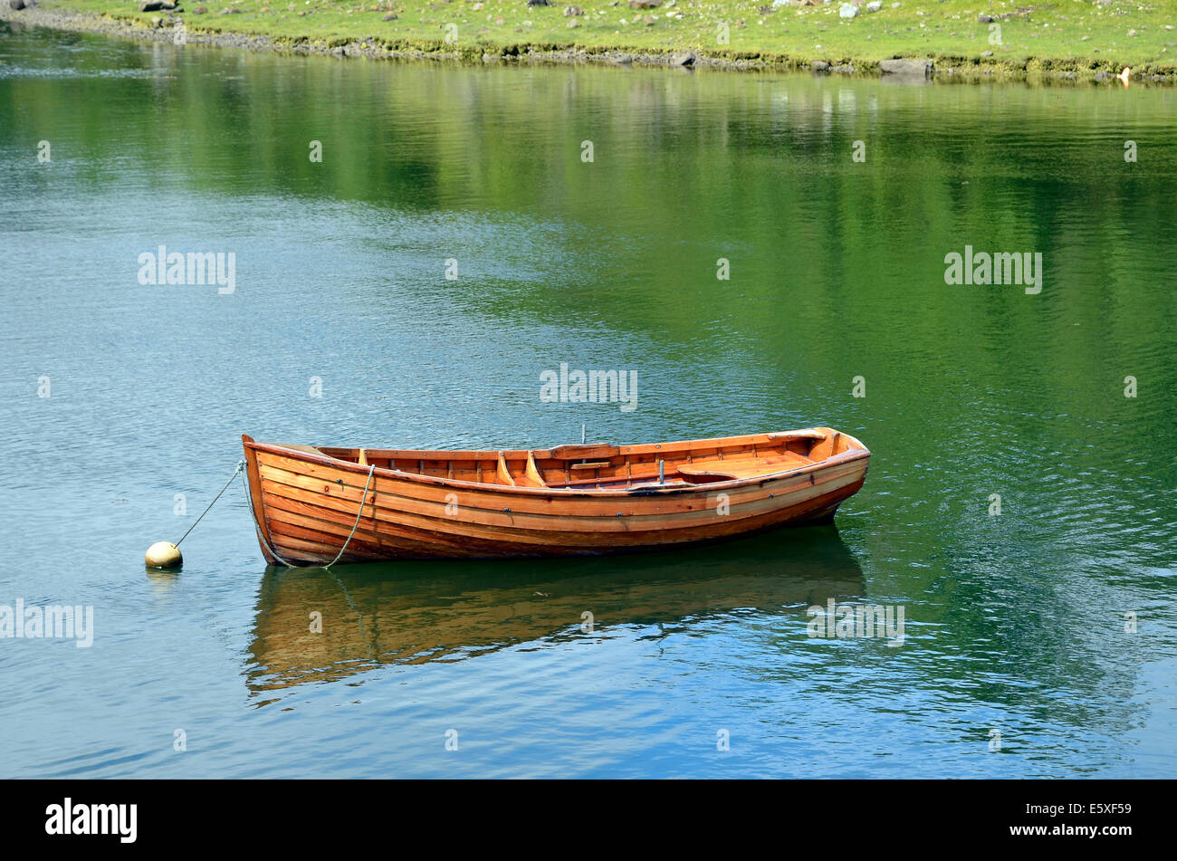 Eine kleine Klinker gebaut aus Holz Ruderboot gebunden an einer Boje festmachen im Hafen von Westport Quay, Mayo, Irland. Stockfoto