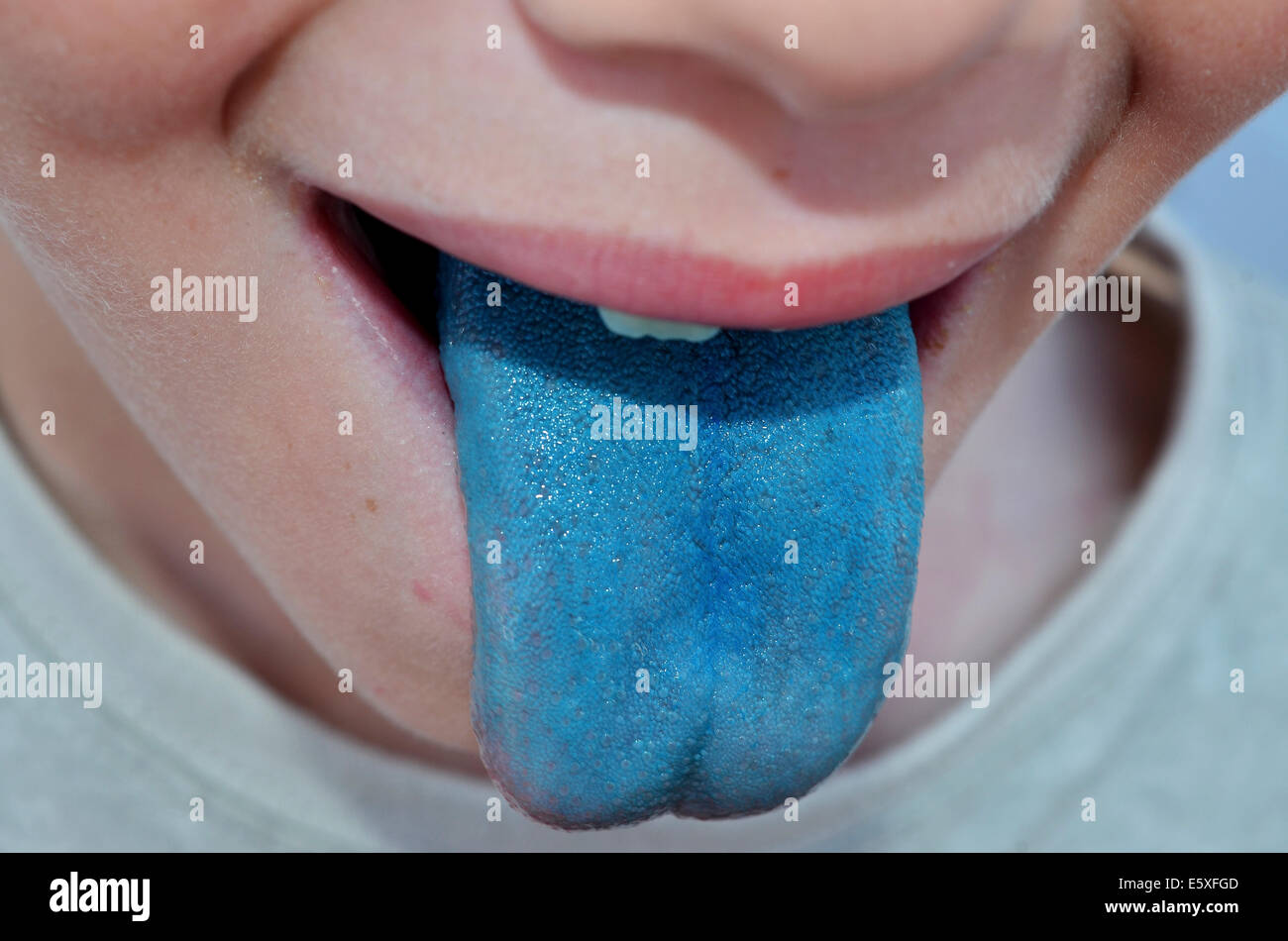 ein kleiner Junge hat Ahd seine Zunge vom saugen eines Lollipop blau eingefärbt Stockfoto