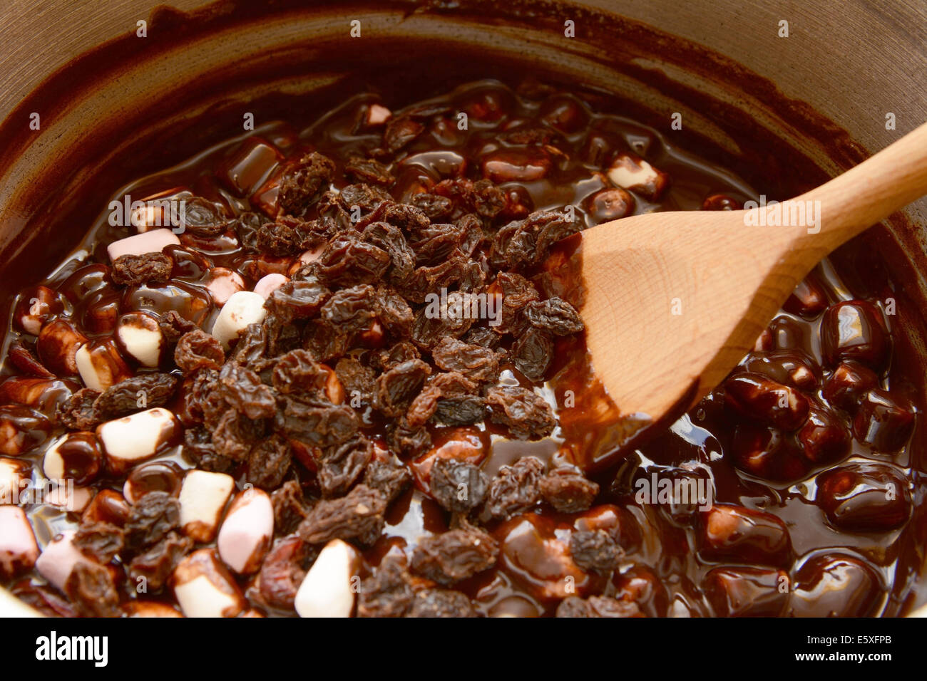 Mischen Rosinen mit Marshmallows und geschmolzene Schokolade, steinigen Weg zu machen Stockfoto