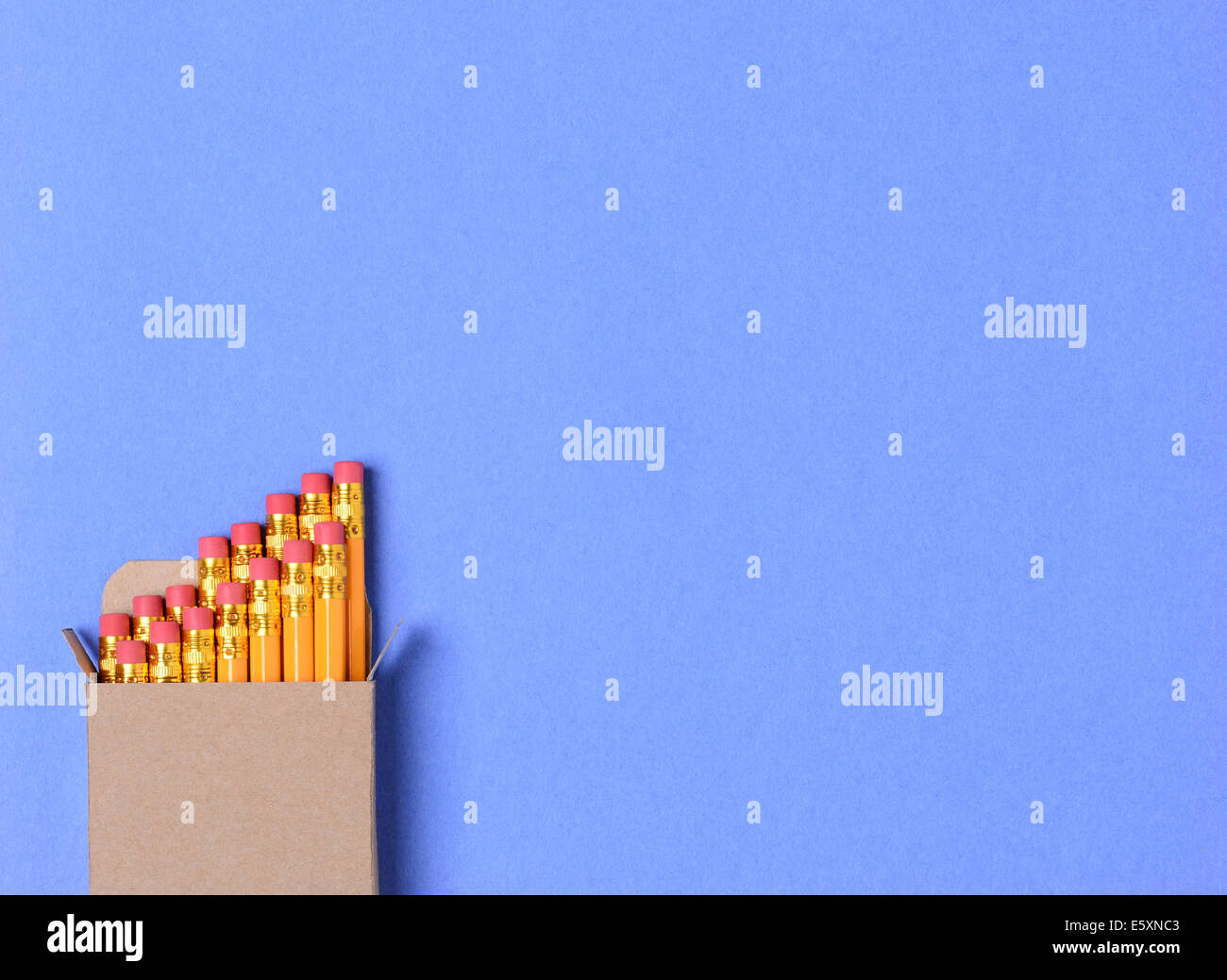 Hohen Winkel Schuss für eine Schachtel mit neuen gelben Bleistifte auf blauem Tonpapier Hintergrund. Querformat mit Textfreiraum. Stockfoto