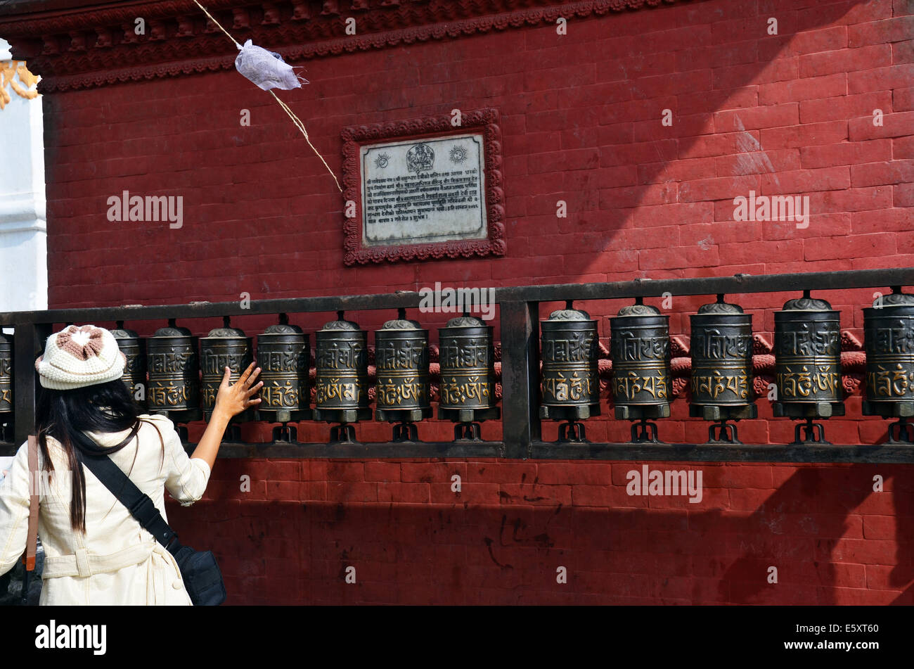 Thai Frau dreht Gebetsmühlen im Swayambhunath Tempel oder Affentempel mit Buddha oder Weisheit Augen Stockfoto