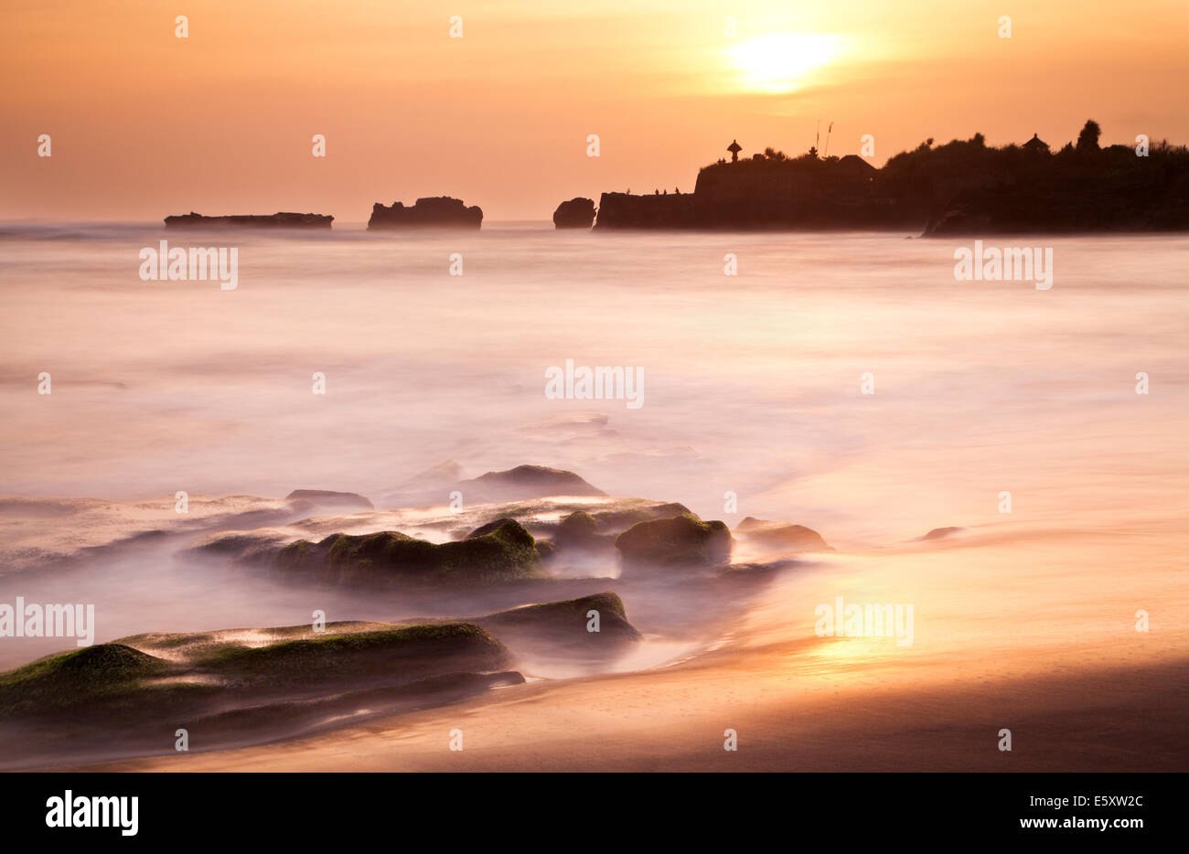 Lange Belichtung Sonnenuntergang Bild der Landspitze in der Nähe des heiligen Küsten Funktion von Tanah Lot Tempel auf Bali. Dies ist ein weiterer Tempel Silhouette mit Orange Sky Stockfoto