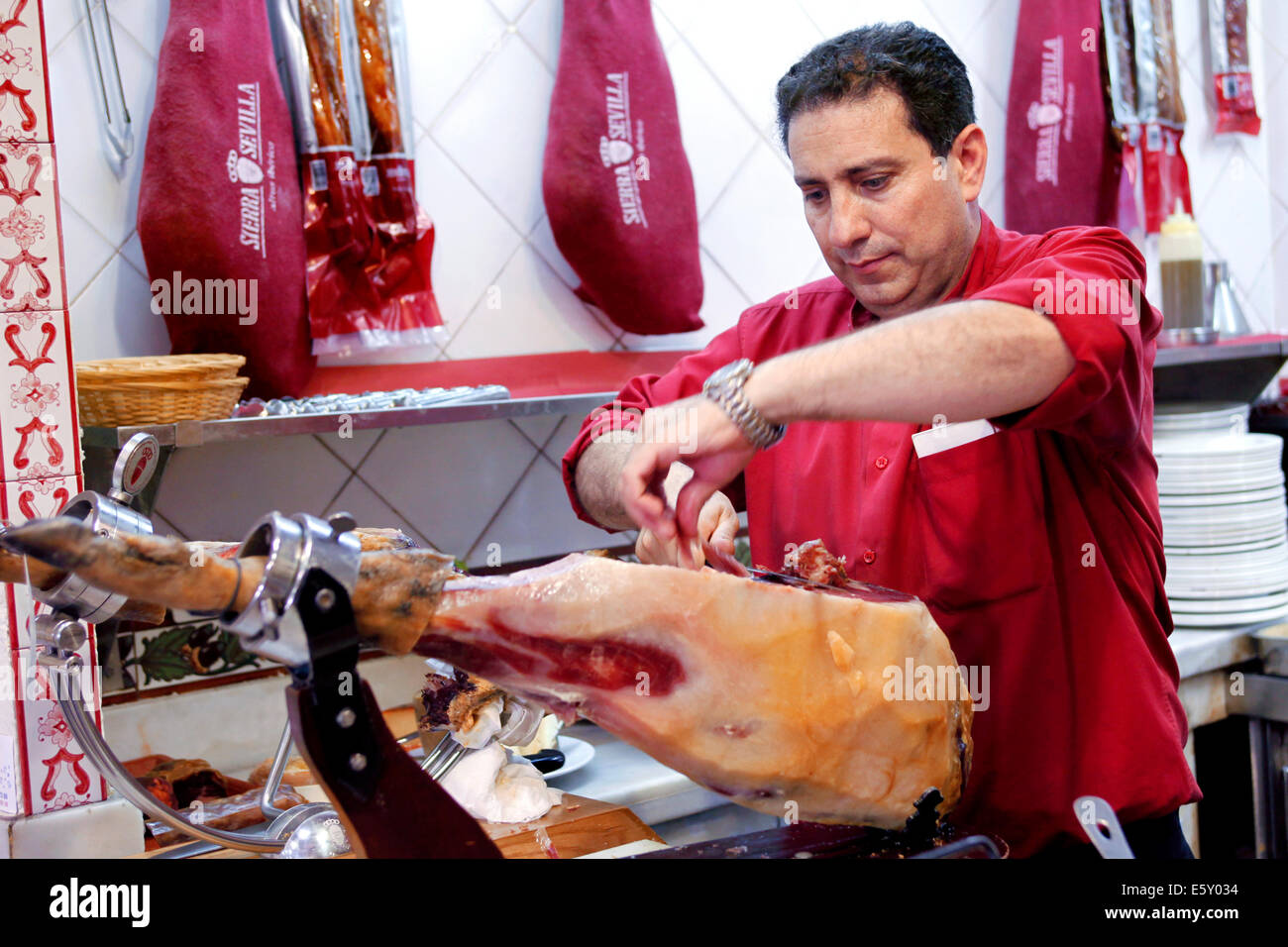 Kellner Carving/Schneiden/Raspeln ein Bein der Jamón Serrano/Jamón Bellota Schinken mit einem Messer, Restaurant Mesón Sierra de Sevilla, Sevilla, Spanien Stockfoto