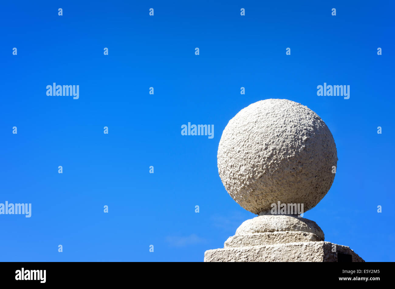 Stein Kugel gegen blauen Himmel auf Sockel Stockfoto