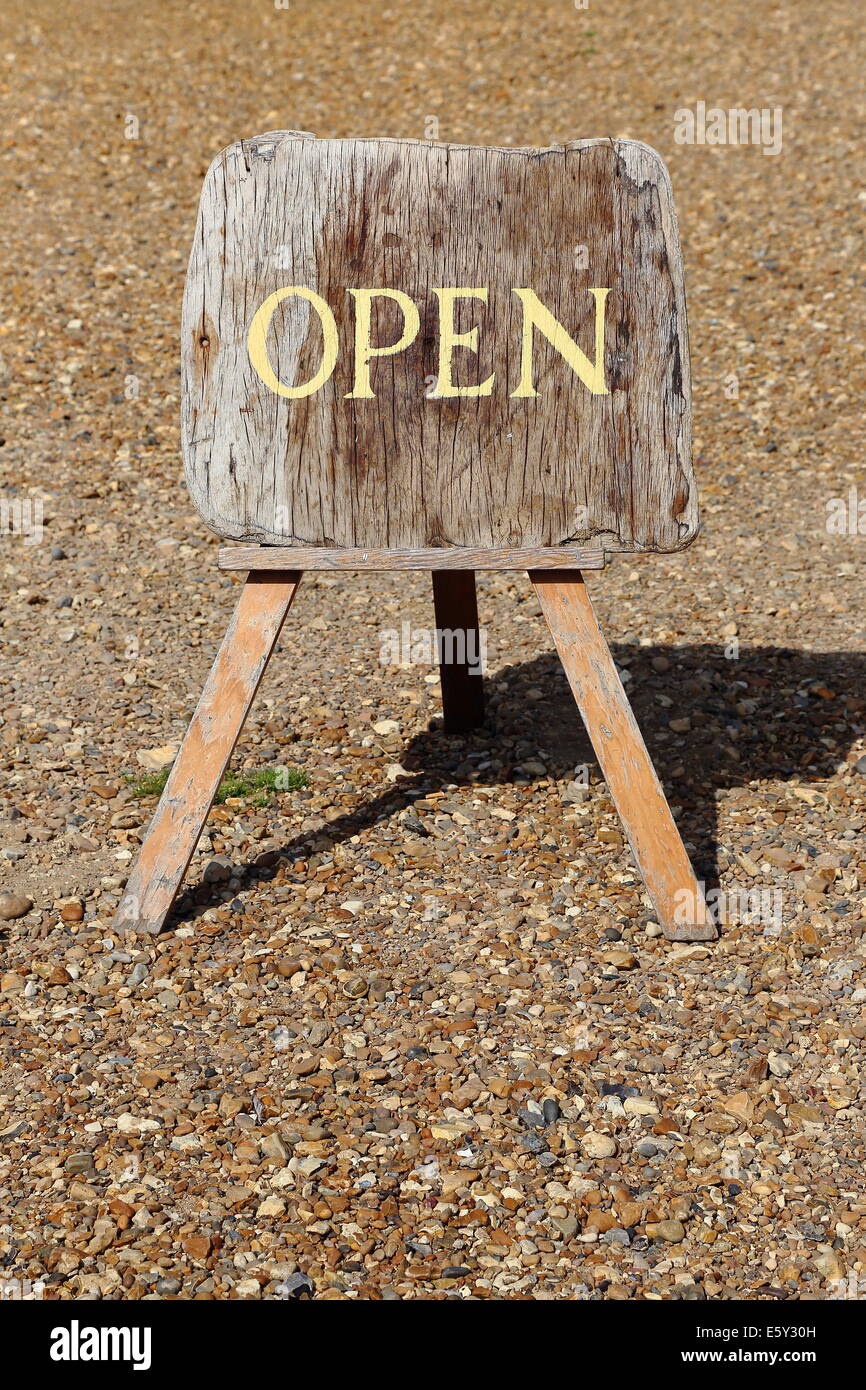 Schild "geöffnet" auf Holzbrett am Kiesstrand Stockfoto