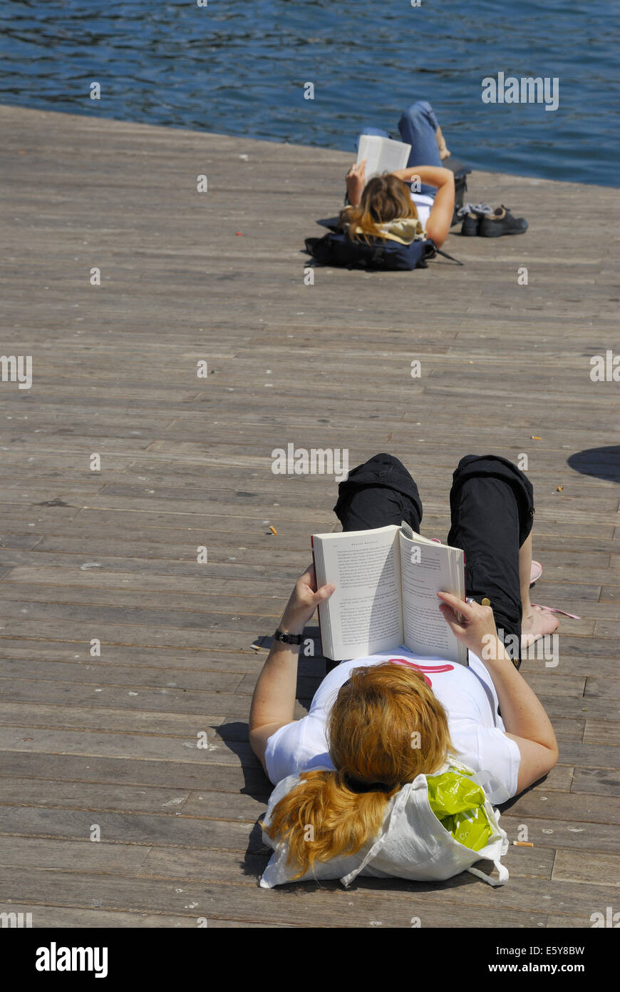 Frau Buch auf Hafenmole oder Promenade, Barcelona, Spanien Stockfoto