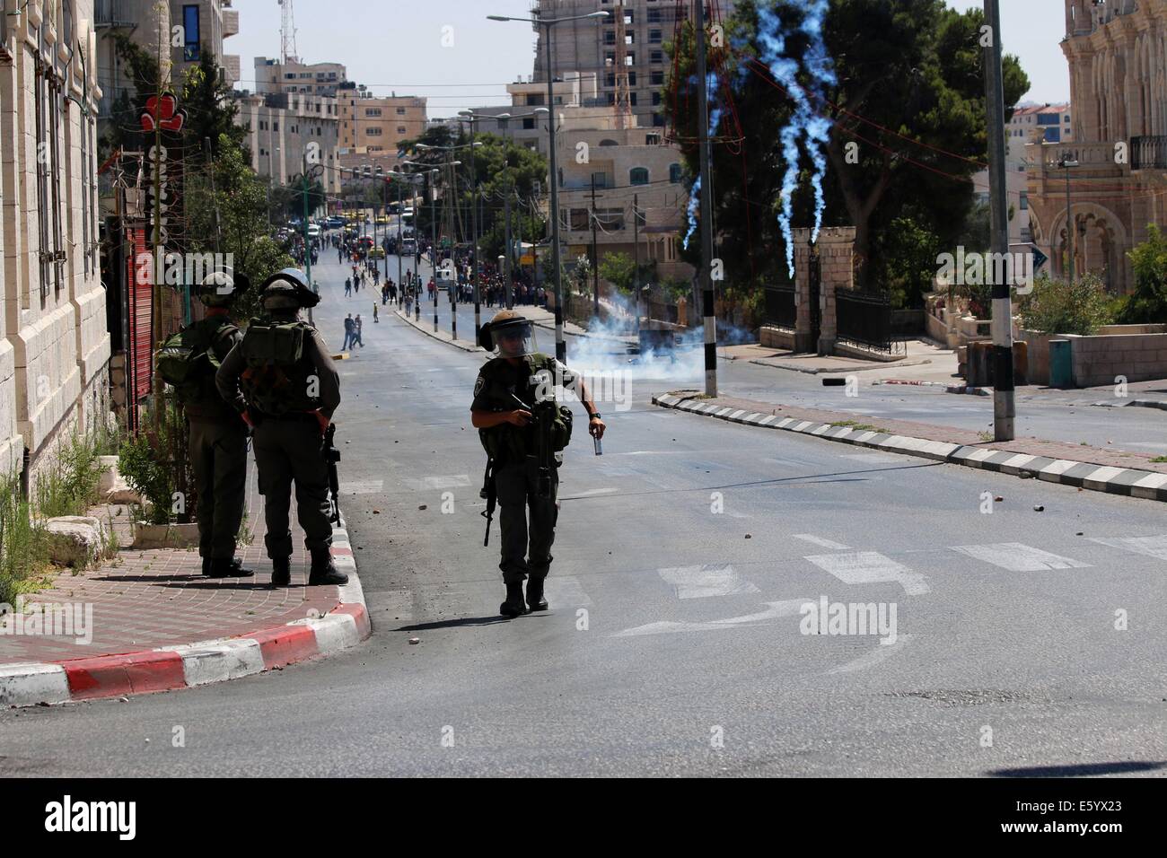 Ein israelischer Soldat nimmt einen leeren Tränengas-Kanister aus seiner Waffe. Hinter ihm regnet Tränengas herab auf die Straßen von Bethlehem. Freitagnachmittag wurde Rage in der West Bank erklärt. Früh am Morgen, nach 08:00, die 72-Stunden Waffenruhe zwischen Gaza und Israel endete und kämpfen wieder aufgenommen. In den frühen Abendstunden israelischen Truppen erschossen und Ahmad Mohammad al-Katar aus al-Amari Flüchtlingslager in der Nähe von Ramallah, als Proteste weiter solidarisch für Gaza im Westjordanland getötet. Während der Proteste gab es in Hebron über 40 verletzte. Inzwischen israelische Luftangriffe getötet ein Kind in der e Stockfoto