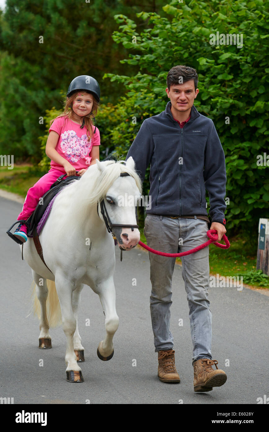 Junges Mädchen Ponyreiten geführt von einem Erwachsenen auf eine Tätigkeit an Center Parcs Sherwood Forest Rufford Nottinghamshire UK Stockfoto