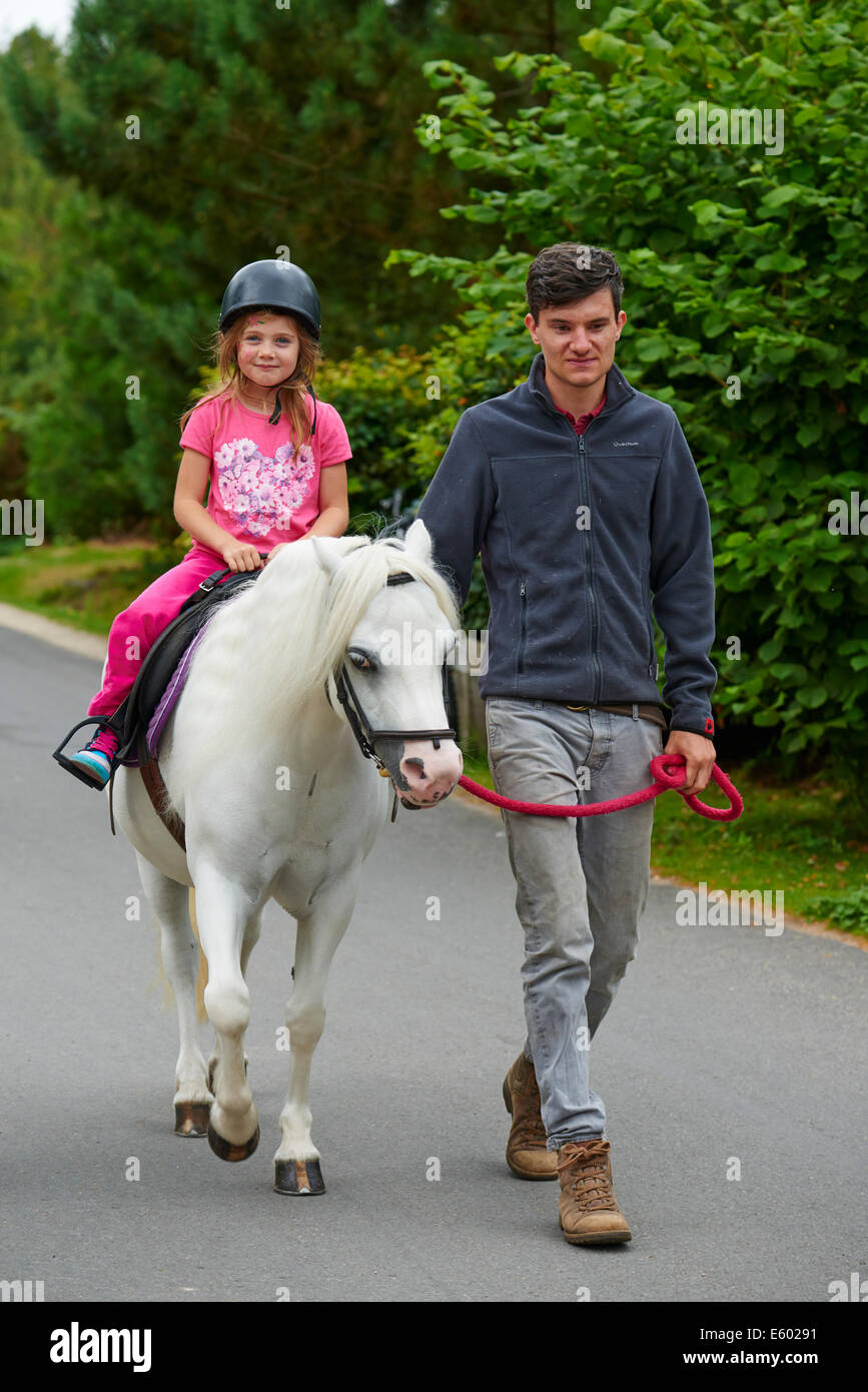 Junges Mädchen Ponyreiten geführt von einem Erwachsenen auf eine Tätigkeit an Center Parcs Sherwood Forest Rufford Nottinghamshire UK Stockfoto