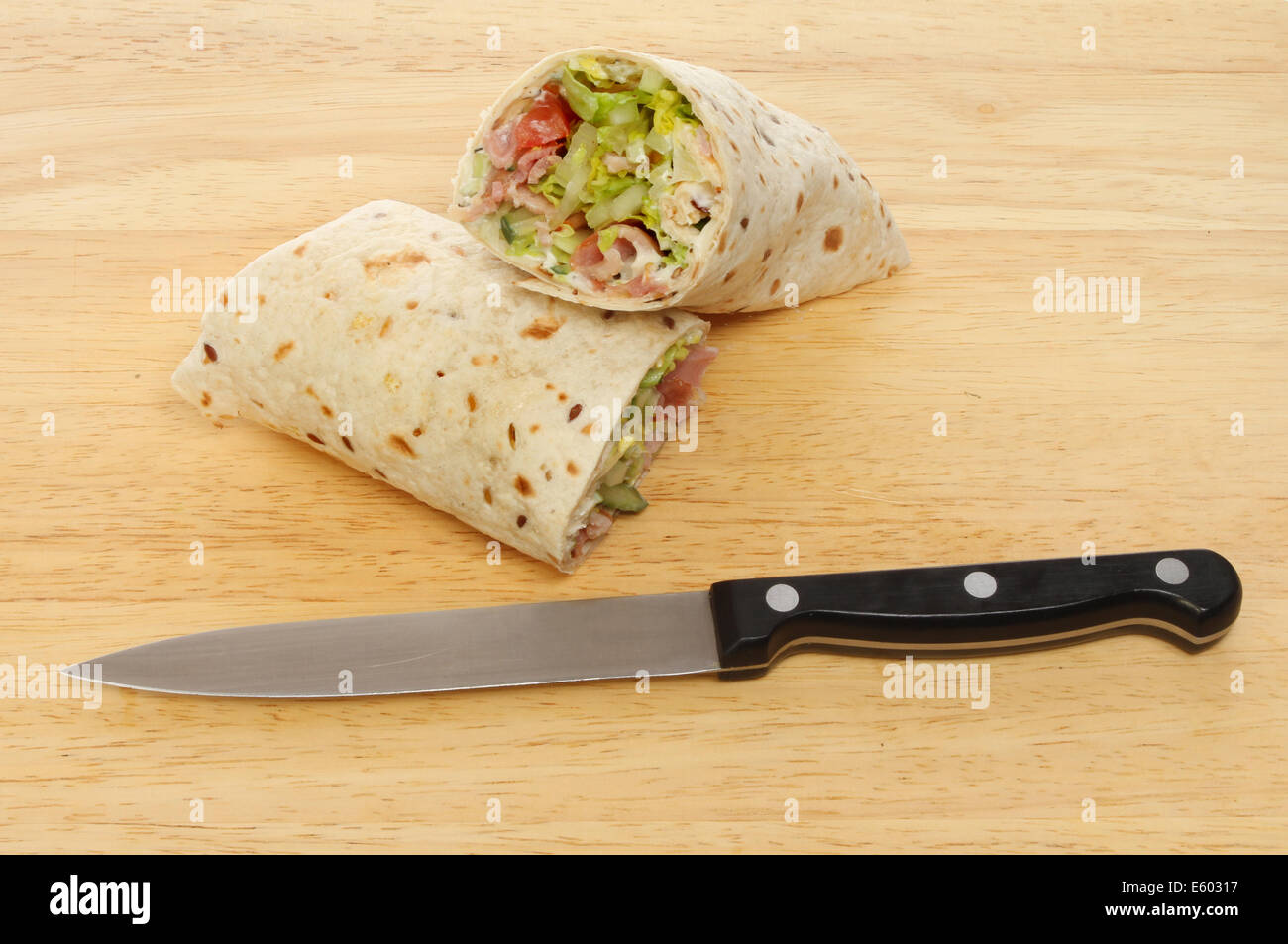 Speck-Salat Brot wickelt auf Holzbrett mit einem Messer Stockfoto