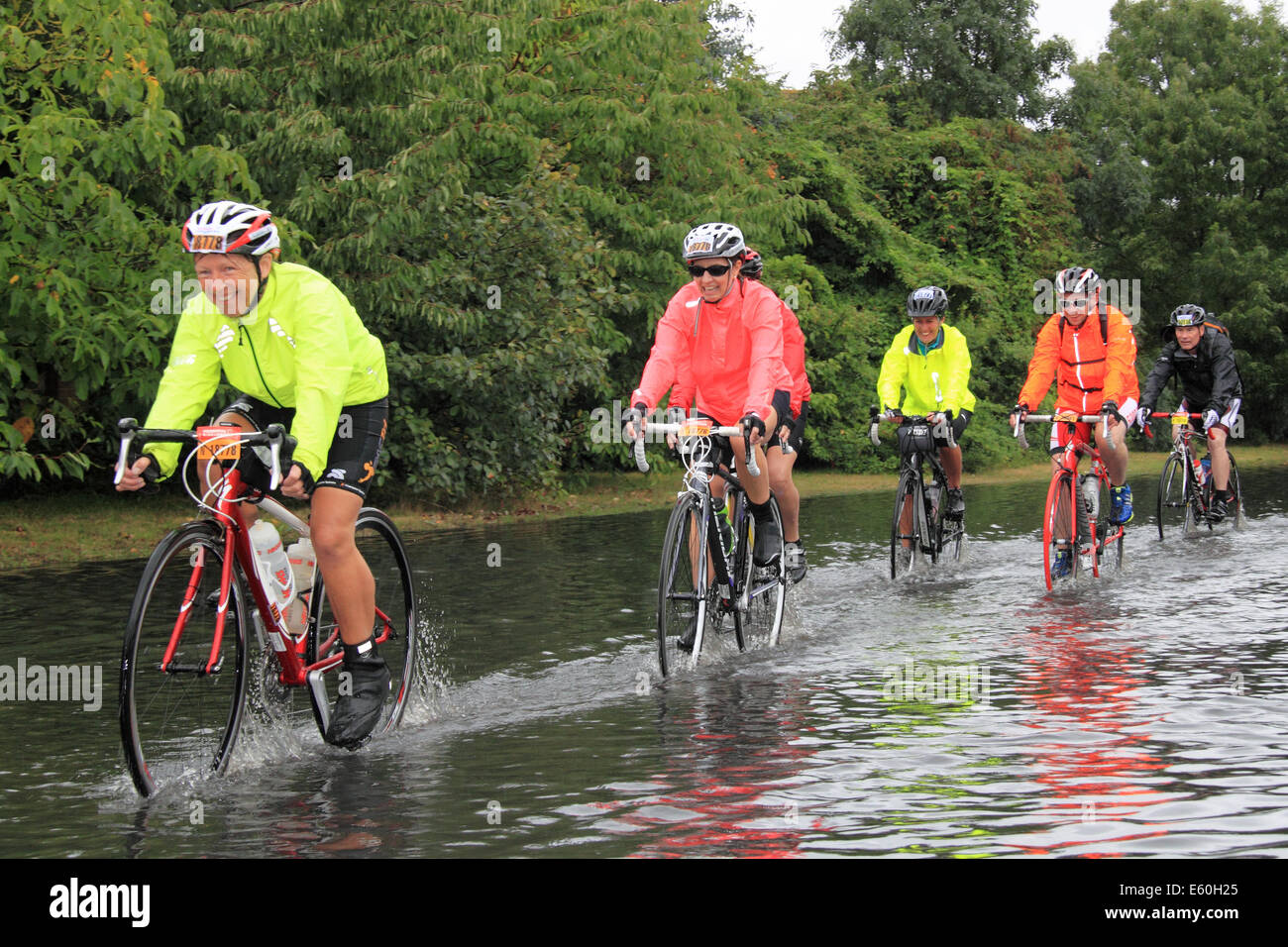 Sonntag, 10. August 2014. East Molesey, Surrey, UK. Radfahrer durchpflügen eine überflutete Straße nach Starkregen durch Reste der Hurrikan Bertha Hits aufsichtsrechtlichen RideLondon-Surrey 100 verursacht. 24.000 Amateur-Radfahrer nahmen Teil an der Veranstaltung der 100miles abdeckt und meistens folgt die Route in London 2012 Olympischen Straßenrennen verwendet. Die Strecke wurde jedoch aufgrund des schlechten Wetters, 86miles verkürzt. Bildnachweis: Ian Flasche/Alamy Live-Nachrichten Stockfoto