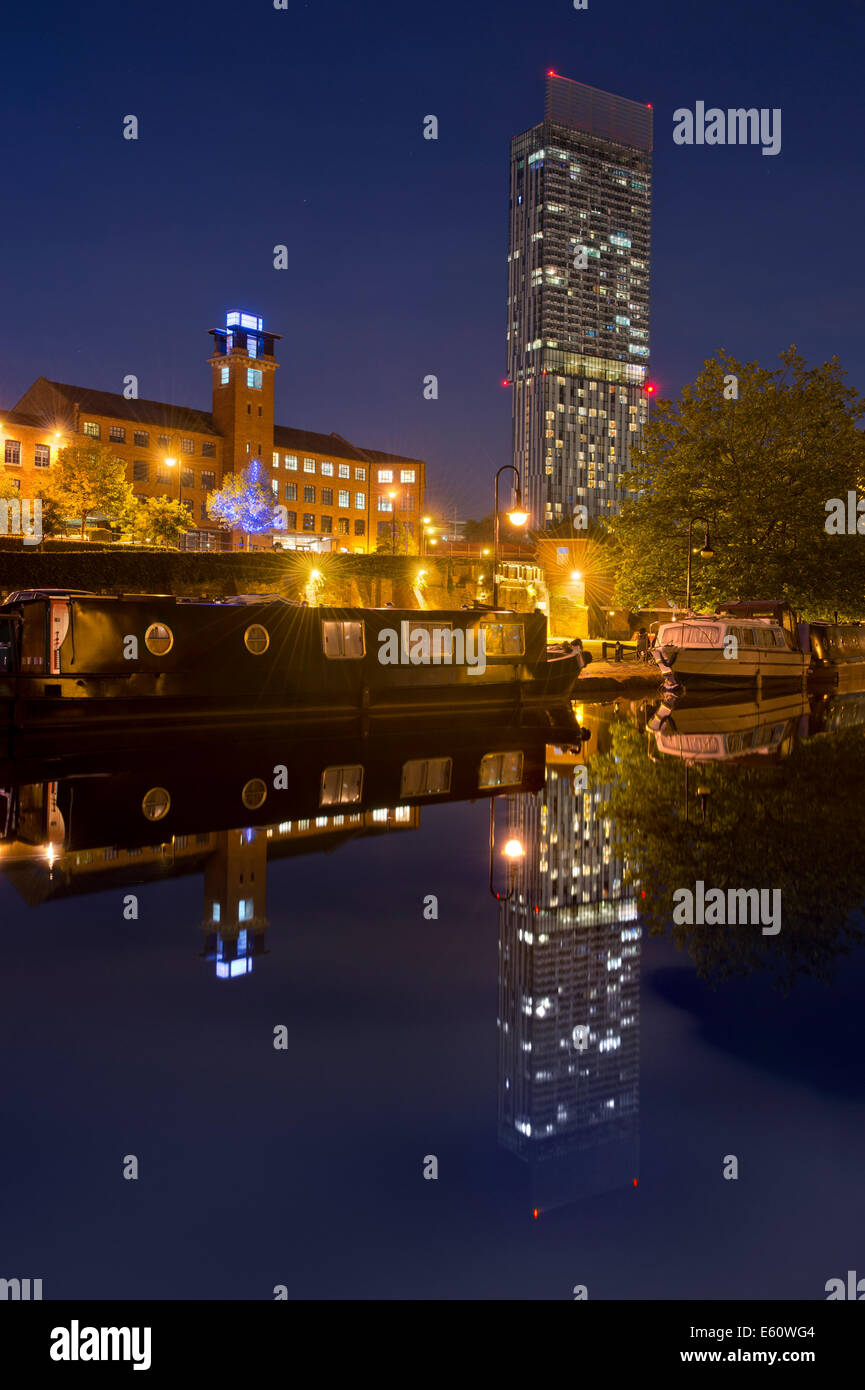 Ein Spiegelbild der Beetham Tower im Wasser am Naturschutzgebiet Castlefield Urban Heritage Park und Kanal in der Nacht, Manchester. Stockfoto