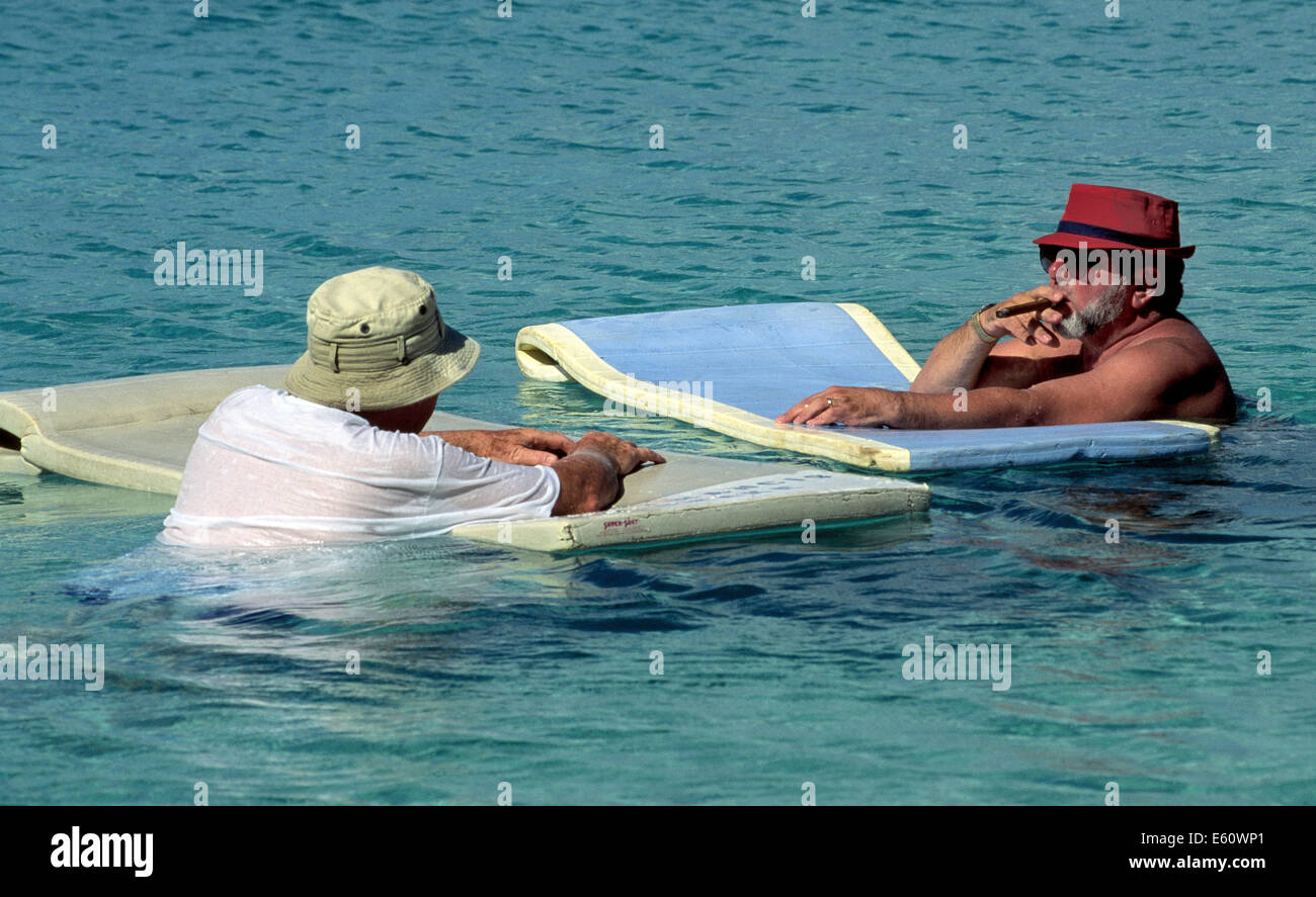 Im Urlaub--zwei ältere Herren einweichen, Schwimmer, und Rauch in das türkisblaue Karibische Meer während des Tragens Hüte zum Schutz vor der tropischen Sonne. Stockfoto