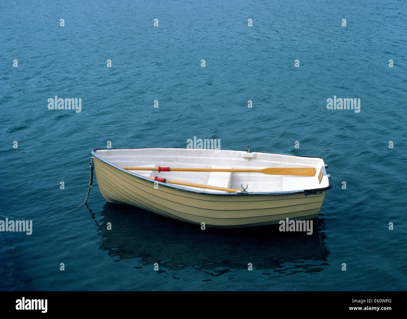 Eine kleine Jolle liegt im flachen Wasser und wartet auf seinen Besitzer zurück und verwenden Sie die hölzerne Ruder zur Zeile zurück zu seiner Segelboot. Stockfoto