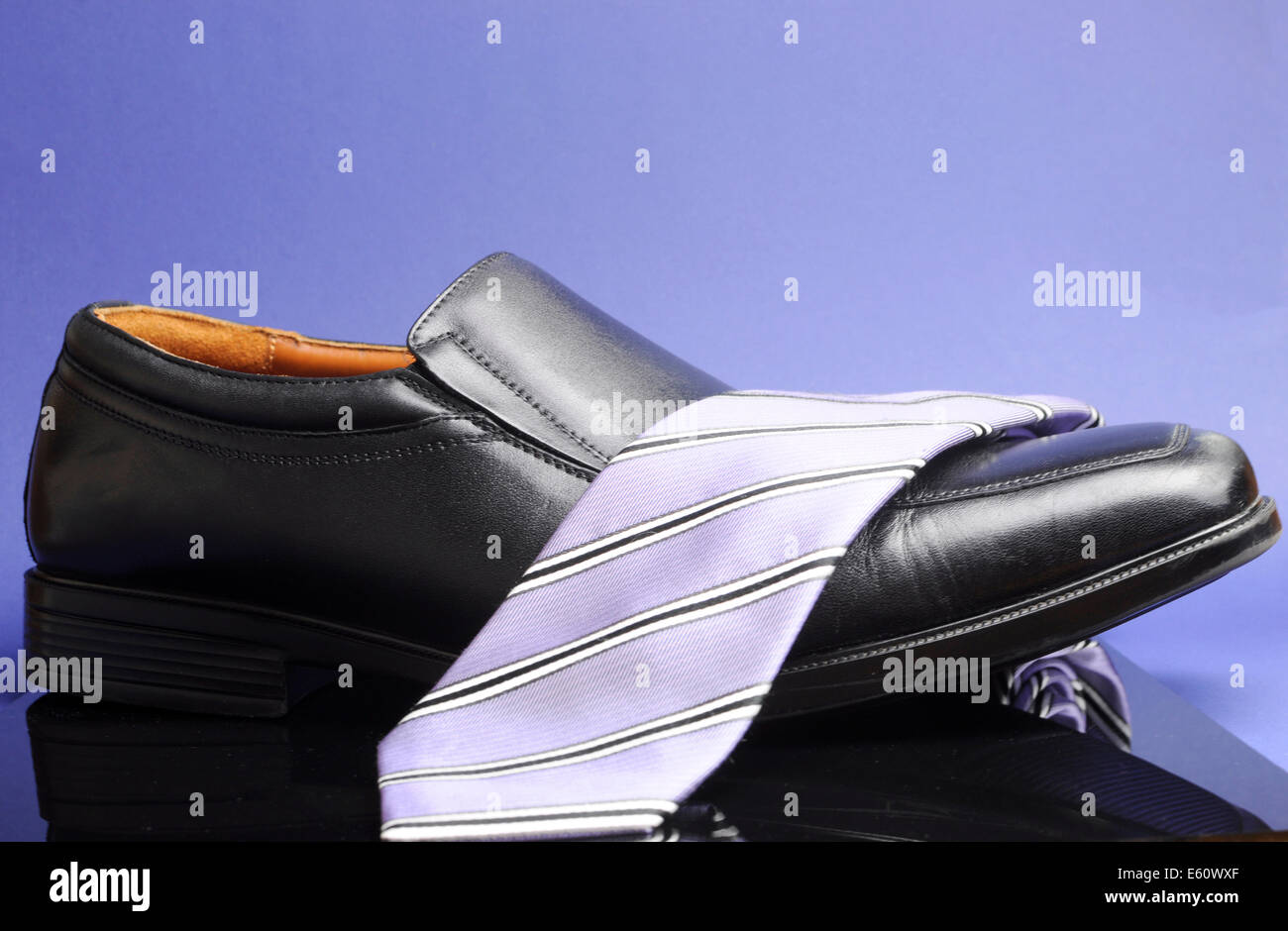 Schwarze Business mans Schuh mit Lavendel Streifen Krawatte vor blauem Hintergrund für Unternehmen, Manager oder Büro Herren Kleidung. Stockfoto