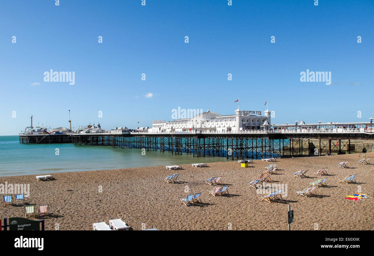 Brighton Pier und leere Liegestühle am Strand von Brighton an einem sonnigen Sommernachmittag mit einem klaren blauen Himmel Stockfoto