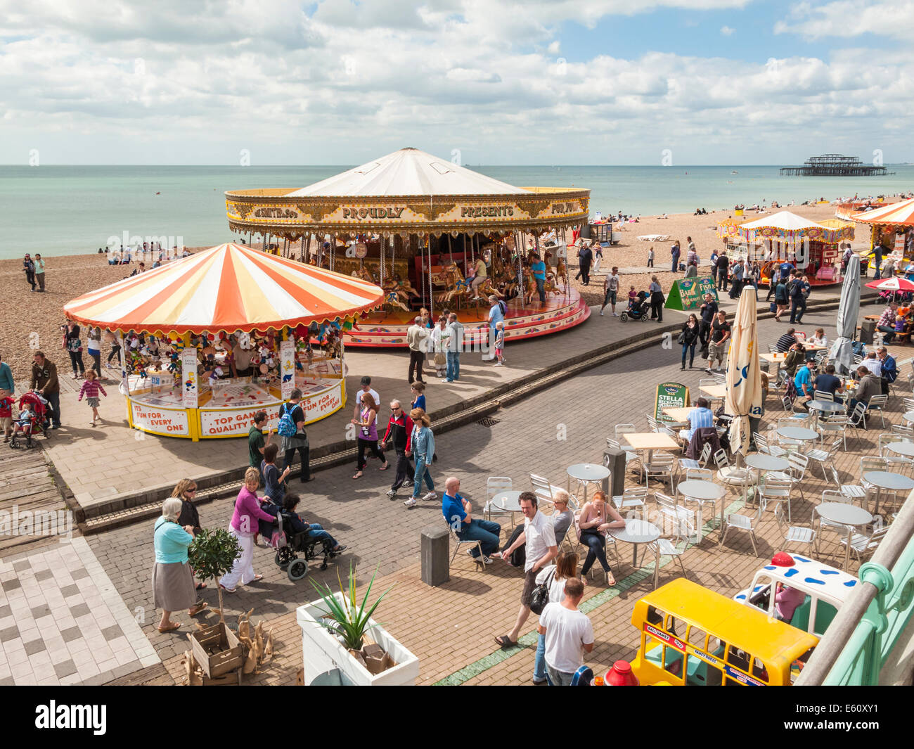 Eine fröhliche Schar von Urlauber genießen Sie einen Spaziergang entlang am Meer und Promenade mit Kirmes-Attraktionen und Souvenirläden Brightons Stockfoto