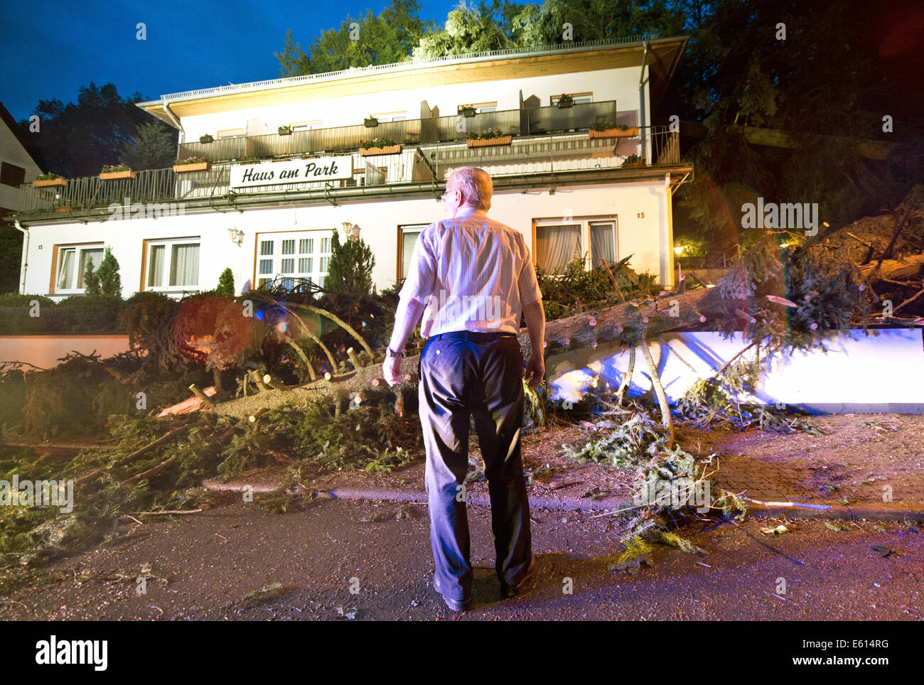 Bad Schwalbach, Deutschland. 10. August 2014. Inhaber Josef Grimm steht vor seinem zerstört teilweise Hotel "Haus am Park" in Bad Schwalbach, Deutschland, 10. August 2014. Kurz nachdem die letzten Gäste gegangen war, fielen mehrere Bäume auf dem Dach des Hotels. Ein Tornado gemeinsam mit einer regen Sturm verursachte Schäden in Millionenhöhe in den Kurort. Zahlreiche Autos wurden beschädigt, Dächer der Häuser abgenommen und Waldflächen zerstört. Foto: Boris Roessler/Dpa/Alamy Live News Stockfoto