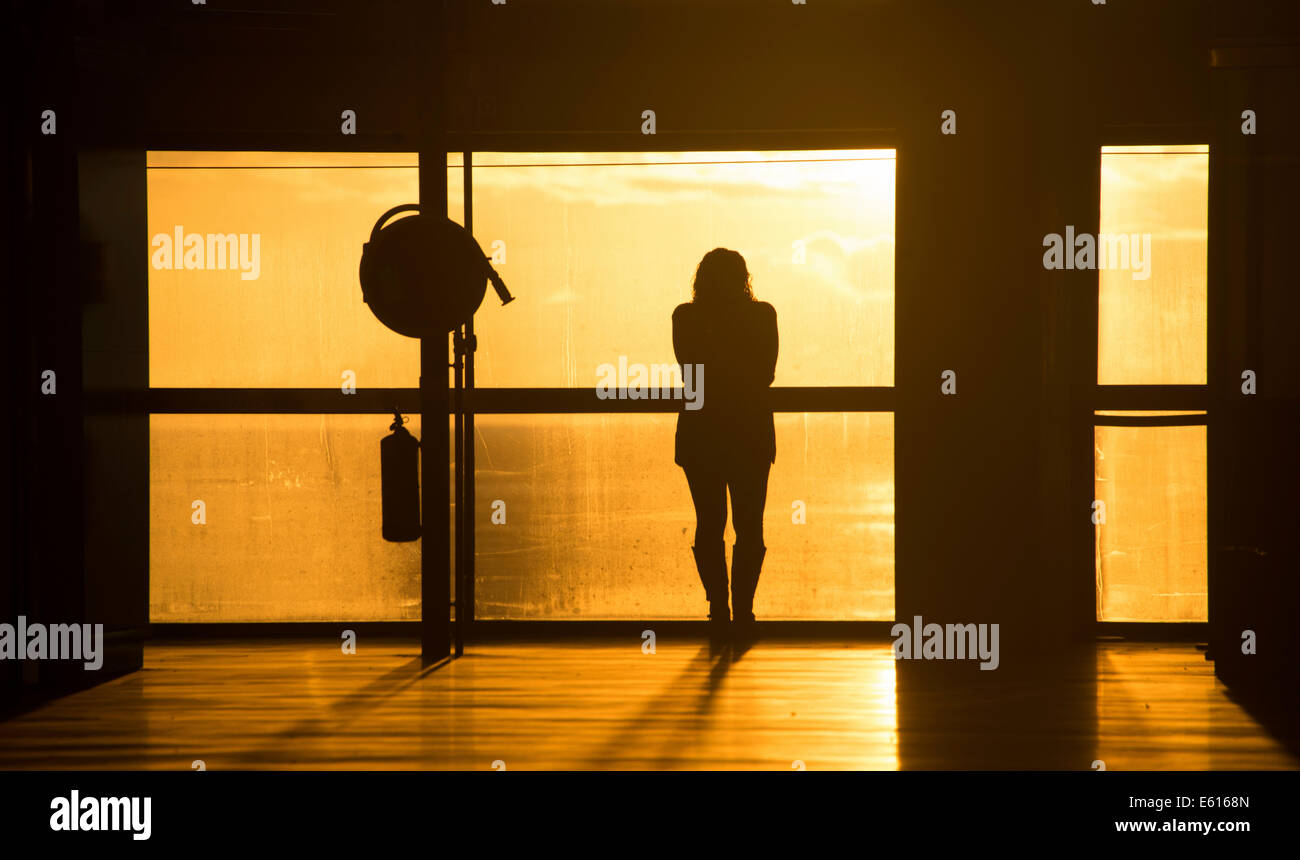 Frau, die durch ein Fenster beobachten den Sonnenaufgang, stimmungsvolles Ambiente, Flughafen von Santa Cruz De La Palma, La Palma, Kanarische Inseln Stockfoto