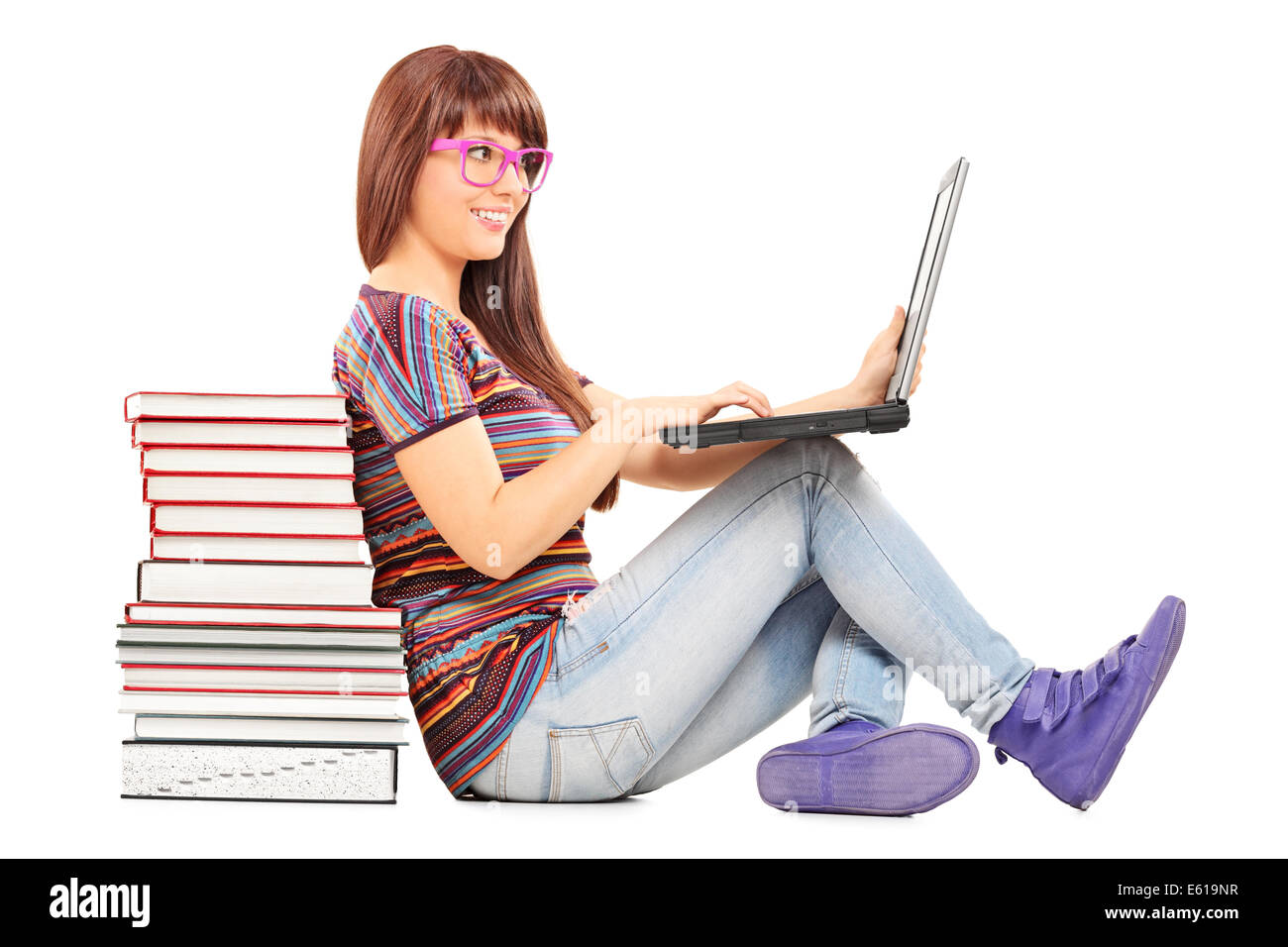 Frau auf einem Laptop zu studieren und stützte sich auf einen Stapel Bücher Stockfoto