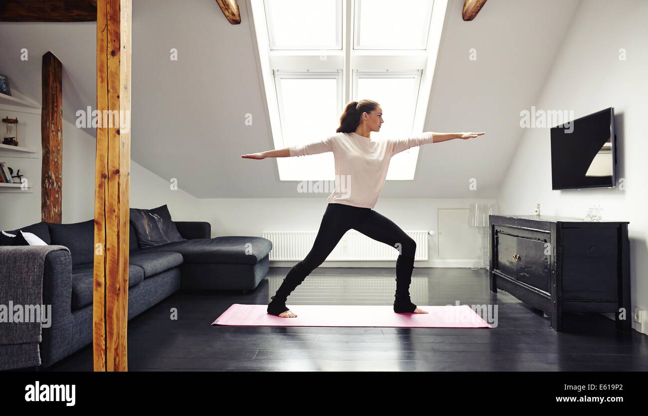 Voller Länge Bild der attraktiven jungen Frau, die Ausübung auf Matte im Wohnzimmer. Passen Sie Dame beim Yoga zu Hause. Stockfoto