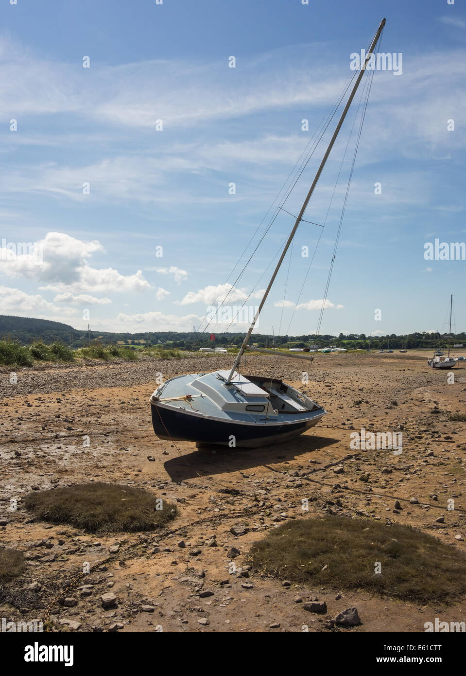 Ein Segelboot durch den zurückweichenden Tide in Rot Wharf Bay, Anglesey, Wales, GB gestrandet. Die Yacht liegt hoch und trocken auf dem Sandstrand in Anglesey, Wales. Stockfoto