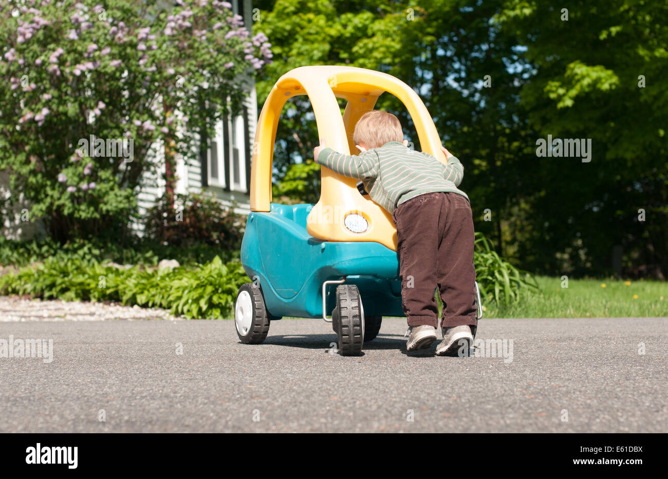 Ein Kleinkind junge lehnt sich über die Front seines großen Spielzeug-Autos, als ob er daran arbeiten wird. Stockfoto