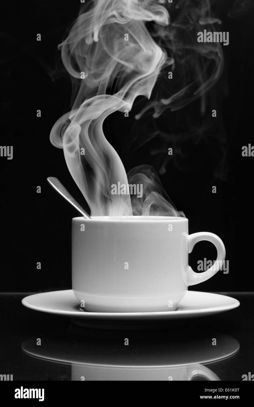 Tasse Heißgetränk mit Dampf auf schwarzem Hintergrund Stockfoto