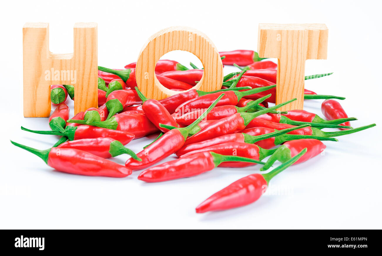 Chilis und heiße Holzbuchstaben - rote frische Chilis mit drei Holzbuchstaben schreiben das Wort HOT. Stockfoto