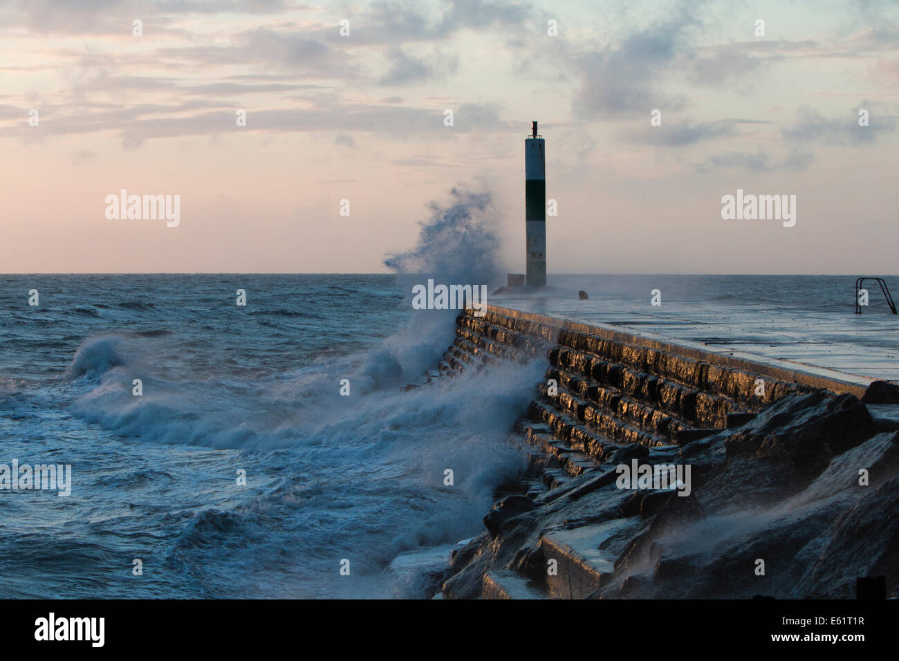 Aberystwyth, Wales, UK. 11. August 2014. Gepeitscht bis durch den Sturm namens Bertha Meer stürzt Wellen gegen den Leuchtturm in Aberystwyth bei Sonnenuntergang. Bildnachweis: Jon Freeman/Alamy Live-Nachrichten Stockfoto