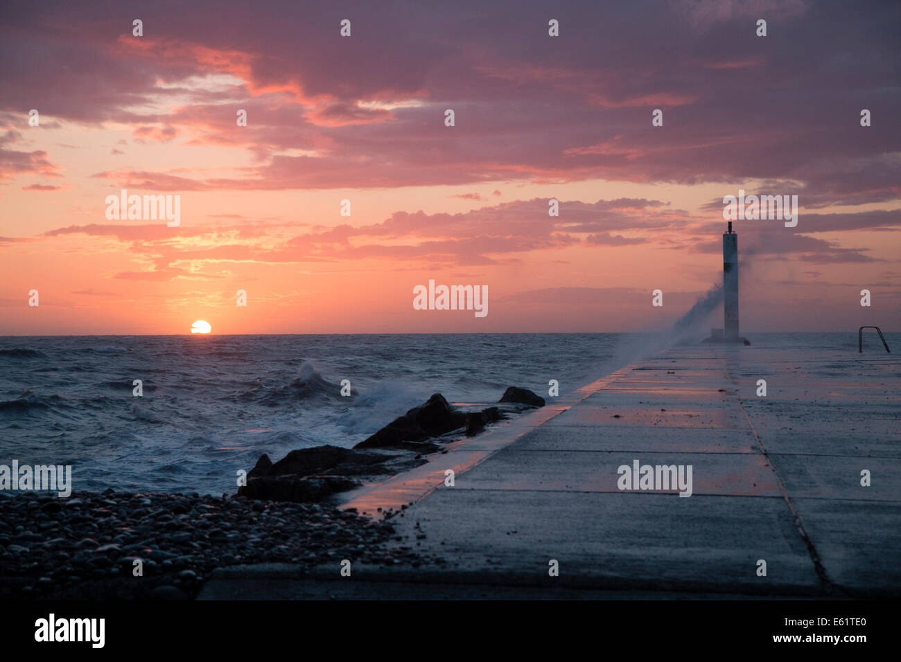 Aberystwyth, Wales, UK. 11. August 2014. Gepeitscht bis durch den Sturm namens Bertha Meer stürzt Wellen gegen den Leuchtturm in Aberystwyth bei Sonnenuntergang. Bildnachweis: Jon Freeman/Alamy Live-Nachrichten Stockfoto