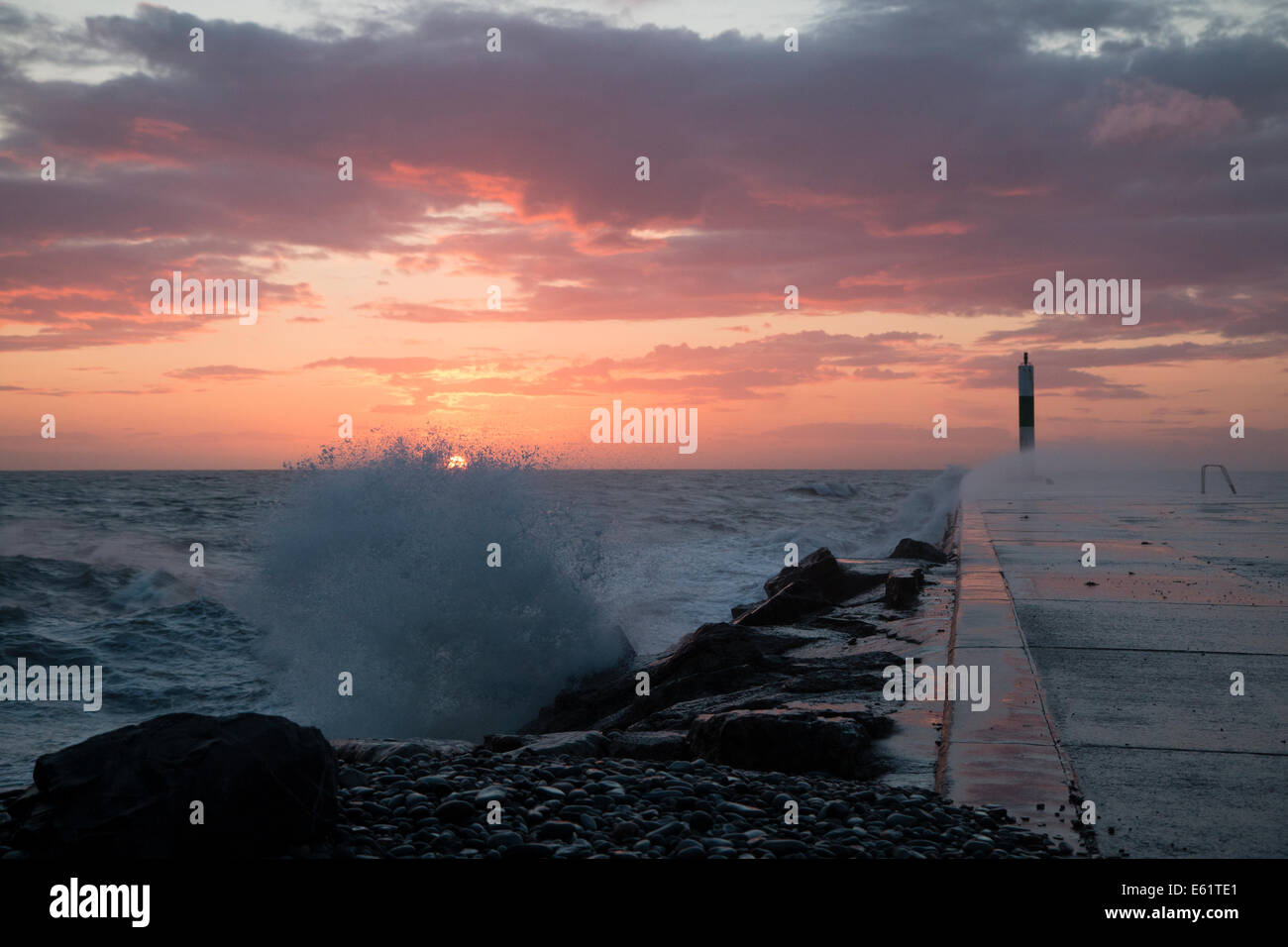 Aberystwyth, Wales, UK. 11. August 2014. Gepeitscht bis durch den Sturm namens Bertha Meer stürzt Wellen gegen den Leuchtturm in Aberystwyth bei Sonnenuntergang. Bildnachweis: Jon Freeman/Alamy Live-Nachrichten Stockfoto