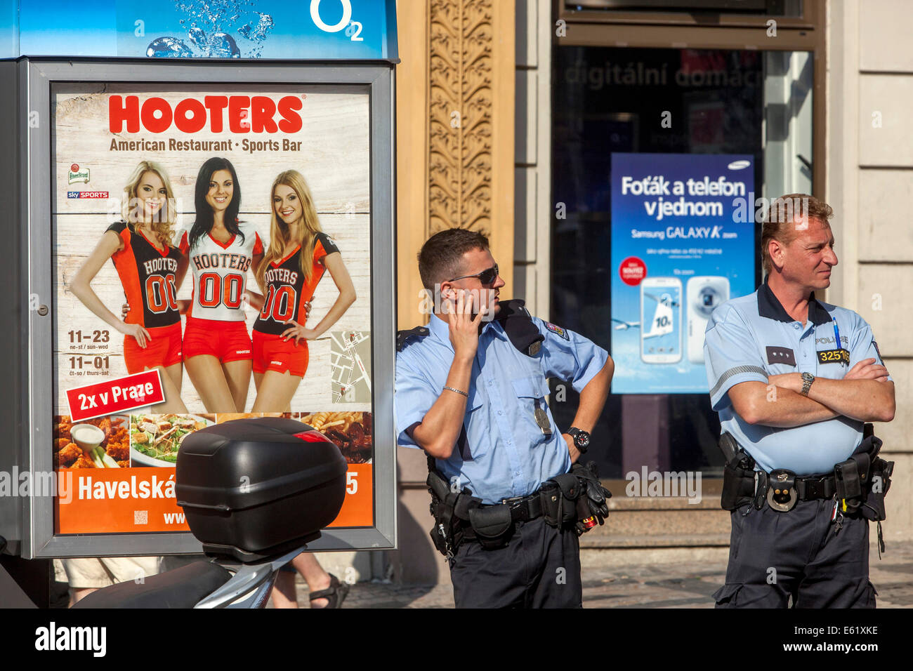 Straßenplakat auf dem Restaurant Hooters, tschechischer Polizeibeamter auf Patrouille, Prag, tschechischer Polizeibeamter auf Straßenpatrouille in Sommeruniform Stockfoto