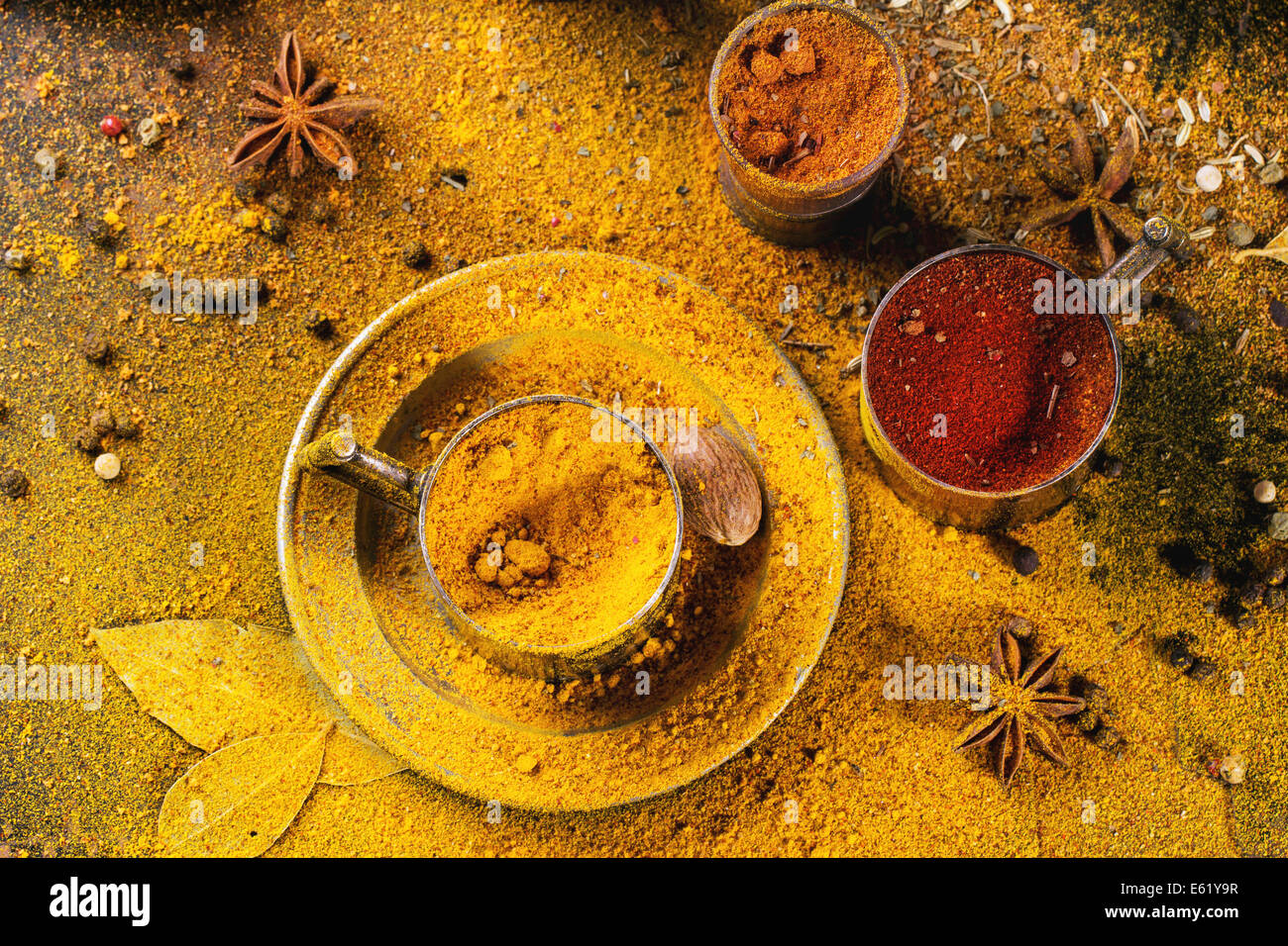 Satz von Gewürzen Pfeffer, Kurkuma, Anis, Koriander in Vintage Metallschalen über gelbe Curry-Pulver. Ansicht von oben. Stockfoto
