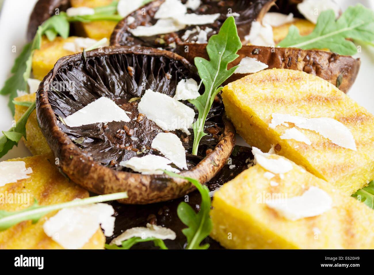 Balsamico marinierte Portobello-Pilze mit gegrillten Scheiben Polenta, Rucola und rasierte Parmesan mit Balsamico Reduktion Stockfoto