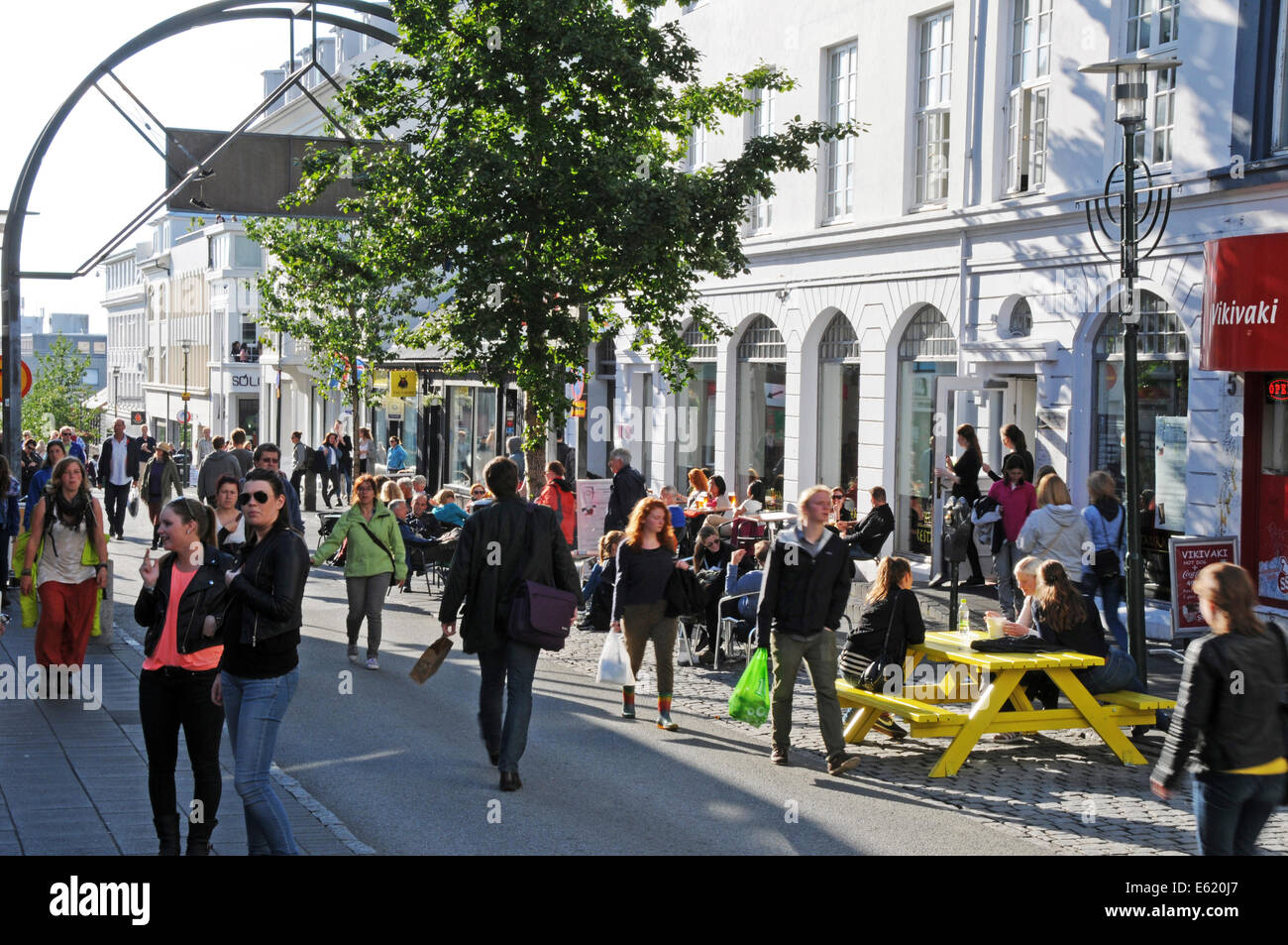 Menschen, Geschäfte, Seite zu Fuß Restaurants und Pubs in Laugavegur Straße im Zentrum von Reykjavik an einem sonnigen Tag in Island Stockfoto