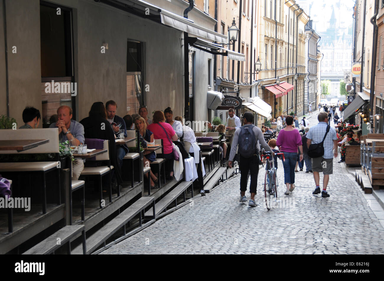Leben auf der Straße im alten Stockholm mit Bürgersteig Restaurants, Coffee-Shops, Fußgänger und Musikern entlang der gepflasterten Straßen Stockfoto