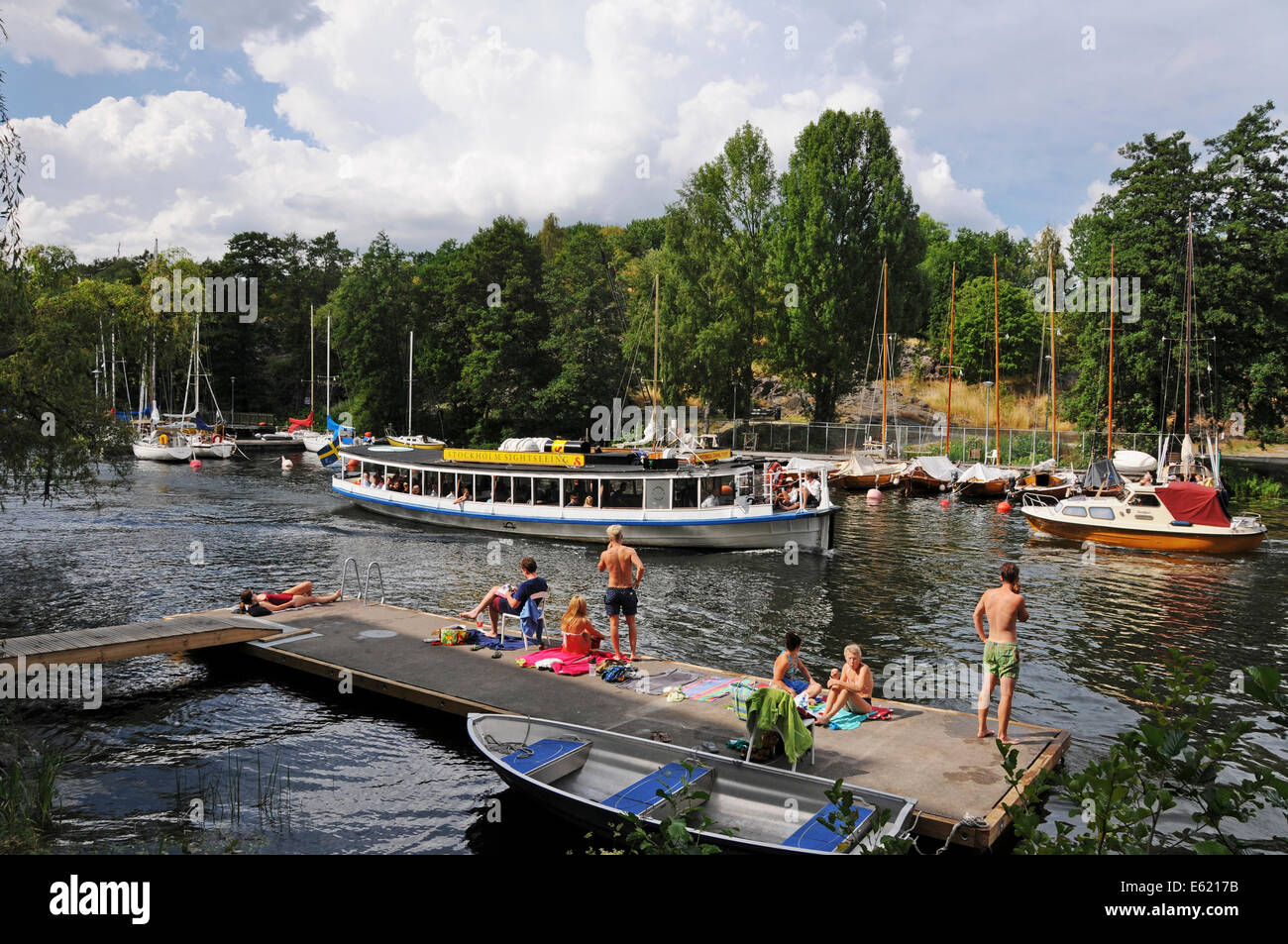 Ausflugsboote und Kajakfahrer auf Långholmen Långholmen Kanal mit Sonnenanbeter in Stockholm Stockfoto