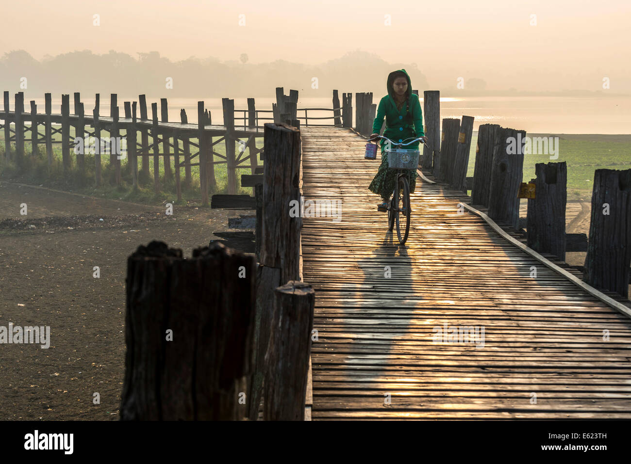 Mädchen mit Tanaka auf ihrem Gesicht, mit dem Fahrrad auf einer Teak Brücke, U Bein Brücke über Thaungthaman See, Amarapura Stockfoto