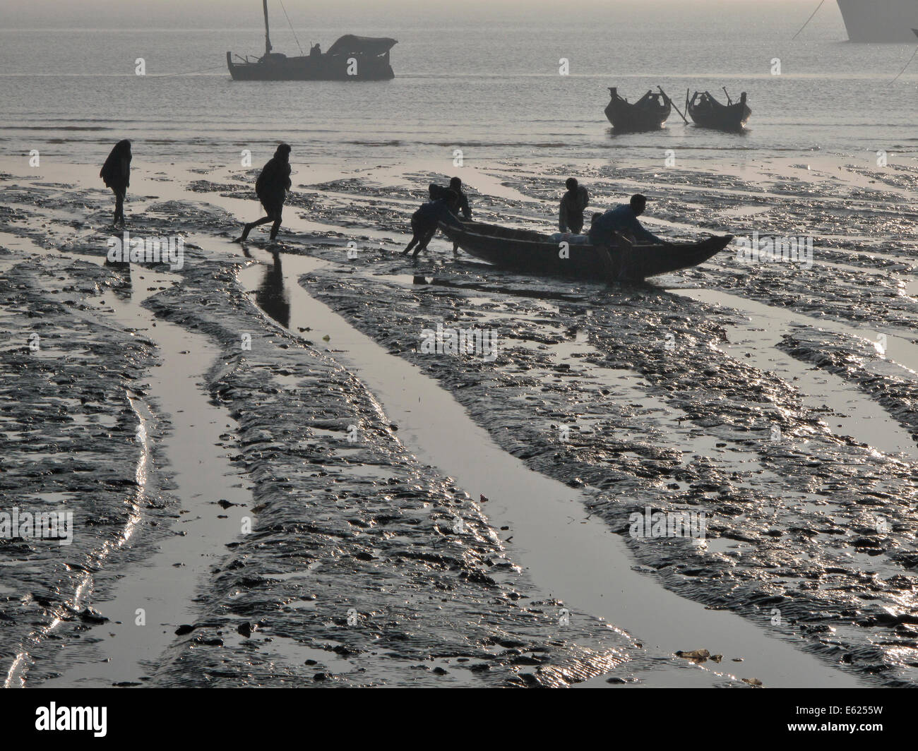 Fischer schieben kleines Boot bei Ebbe, schlammigen Ufer, von Birma Stockfoto