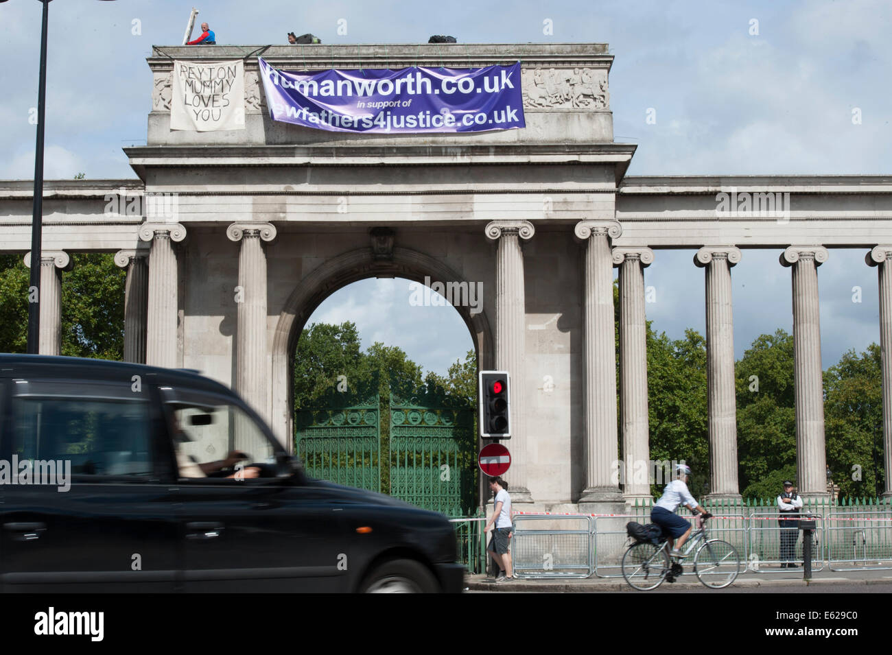 Hyde Park Corner, London, UK. 12. August 2014. Demonstranten, die sich selbst neue Väter 4 Gerechtigkeit skalieren Londons Wahrzeichen Eingang zum Hyde Park. Einer der Demonstranten war in einem Spider-Man-Anzug gekleidet und Gestikulieren V für Sieg an Passanten gesehen wurde. Bildnachweis: Lee Thomas/Alamy Live-Nachrichten Stockfoto