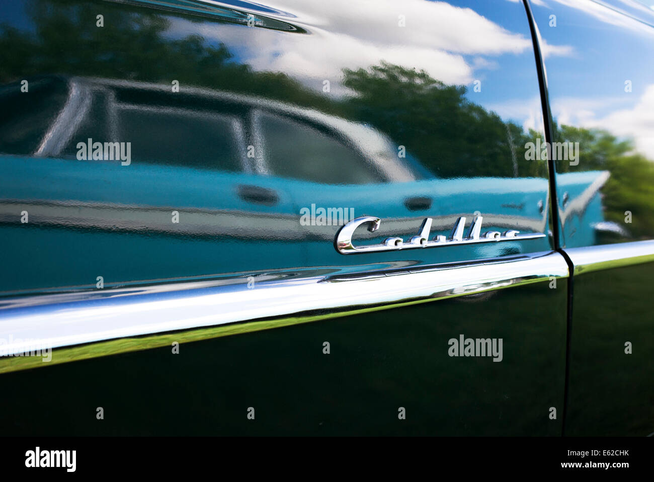 Chrom-Cadillac-Abzeichen und trim mit einem blauen Ford Chevrolet spiegelt sich in der schwarzen Lackierung Stockfoto