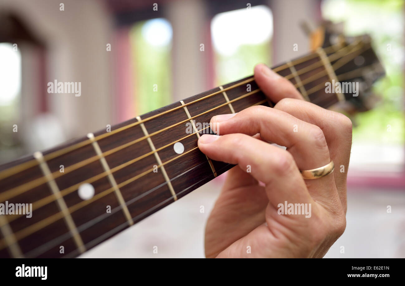 Nahaufnahme der männlichen Musiker spielt akustische Gitarre mit Akkord Fingersatz auf dem Griffbrett Stockfoto