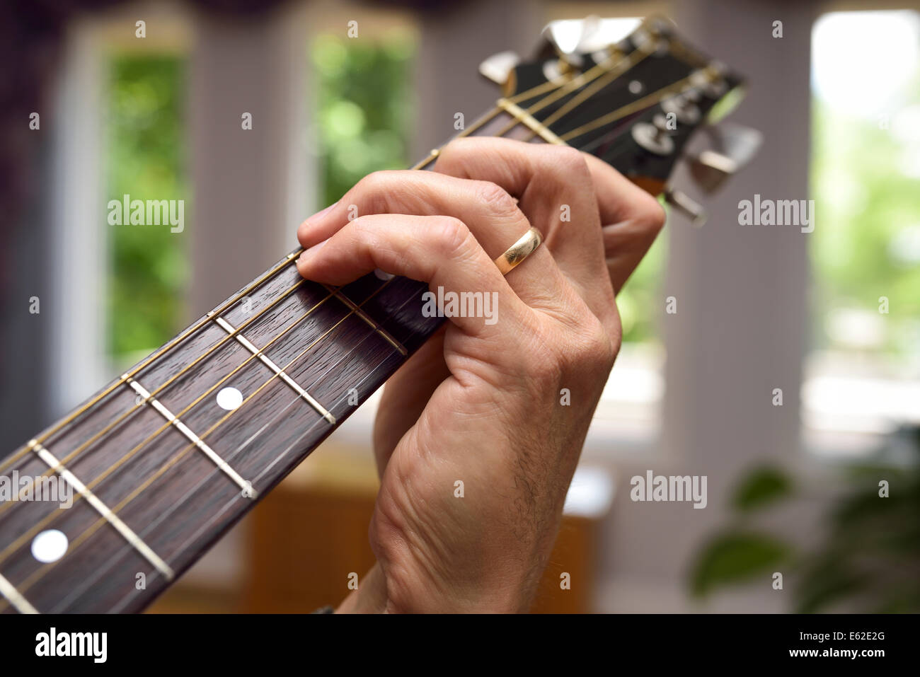 Nahaufnahme eines Mannes spielt akustische Gitarre mit Akkord Fingersatz auf dem Griffbrett Stockfoto