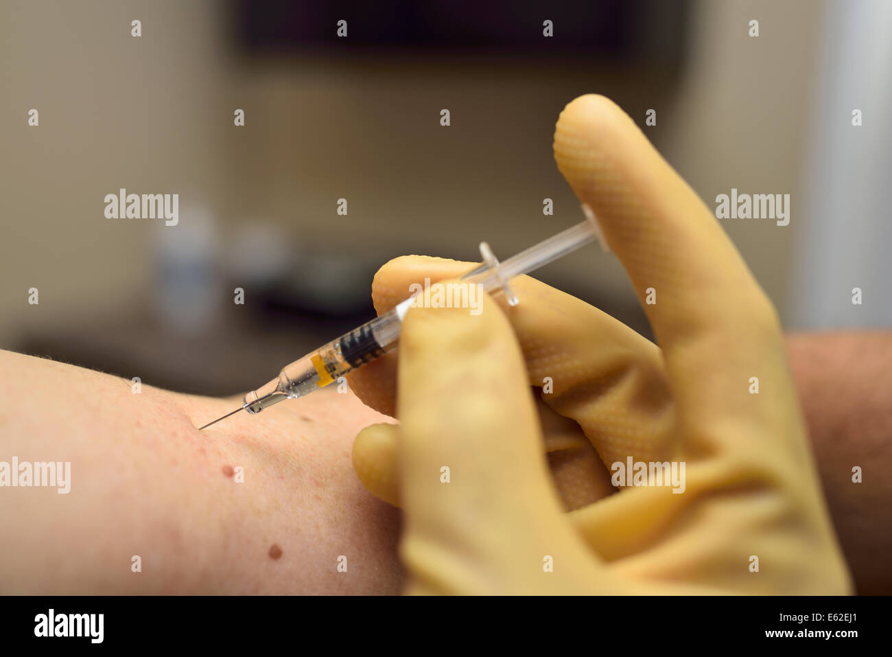 Behandschuhte Hand Einspritzen von Medizin in den Arm eines älteren Mannes mit einer Spritze in einer Klinik Stockfoto