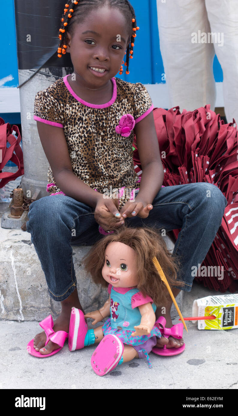 kleine schwarze Mädchen Flechten Haare weiße Puppe, Nassau, Providence Island, Bahamas Stockfoto