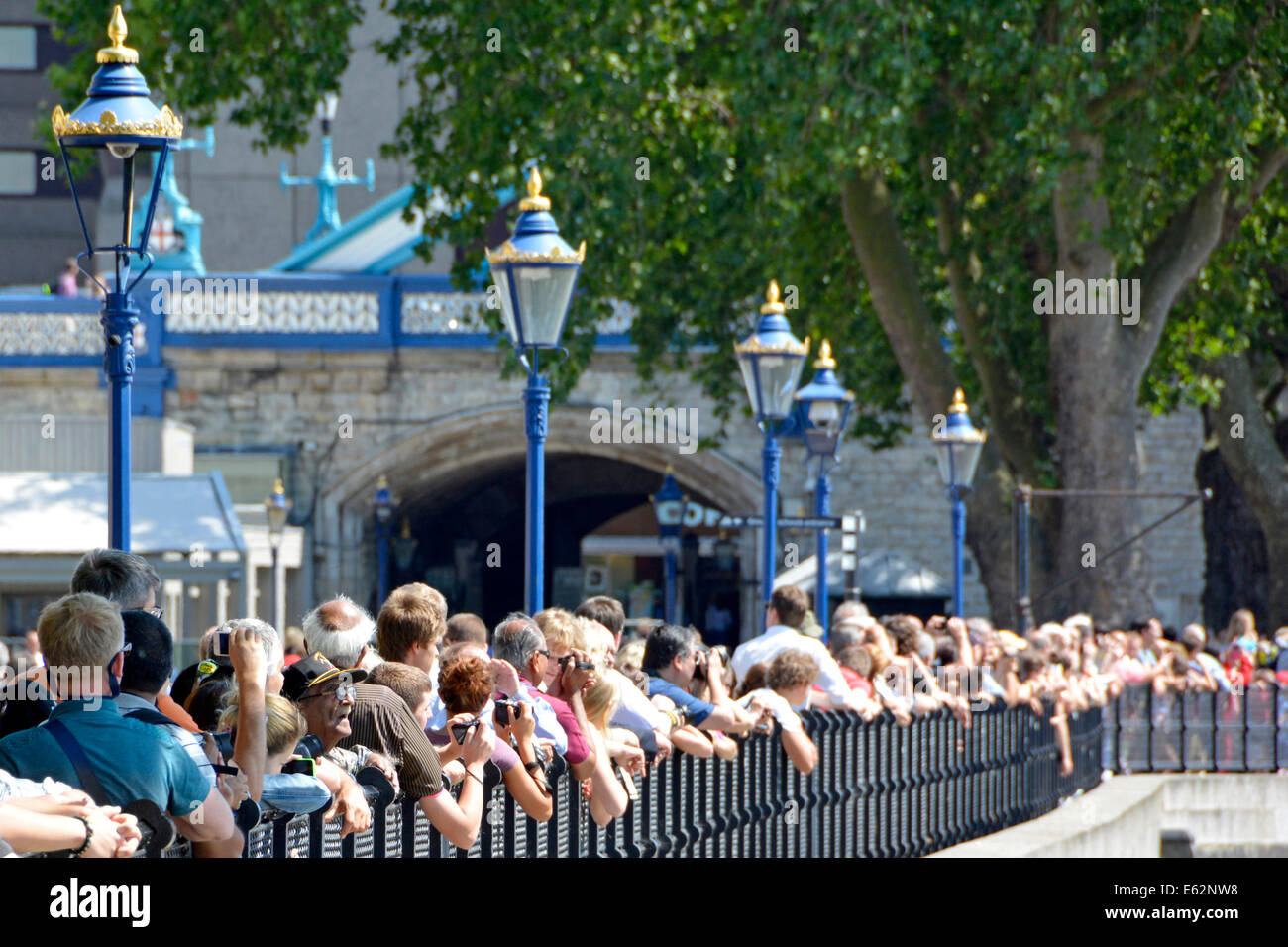 Alter junge Gesicht unter der Masse der Touristen entlang der Flussufer Geländer zu schnappen, die Anhebung der Tower Bridge für ein Kreuzfahrtschiff Stockfoto