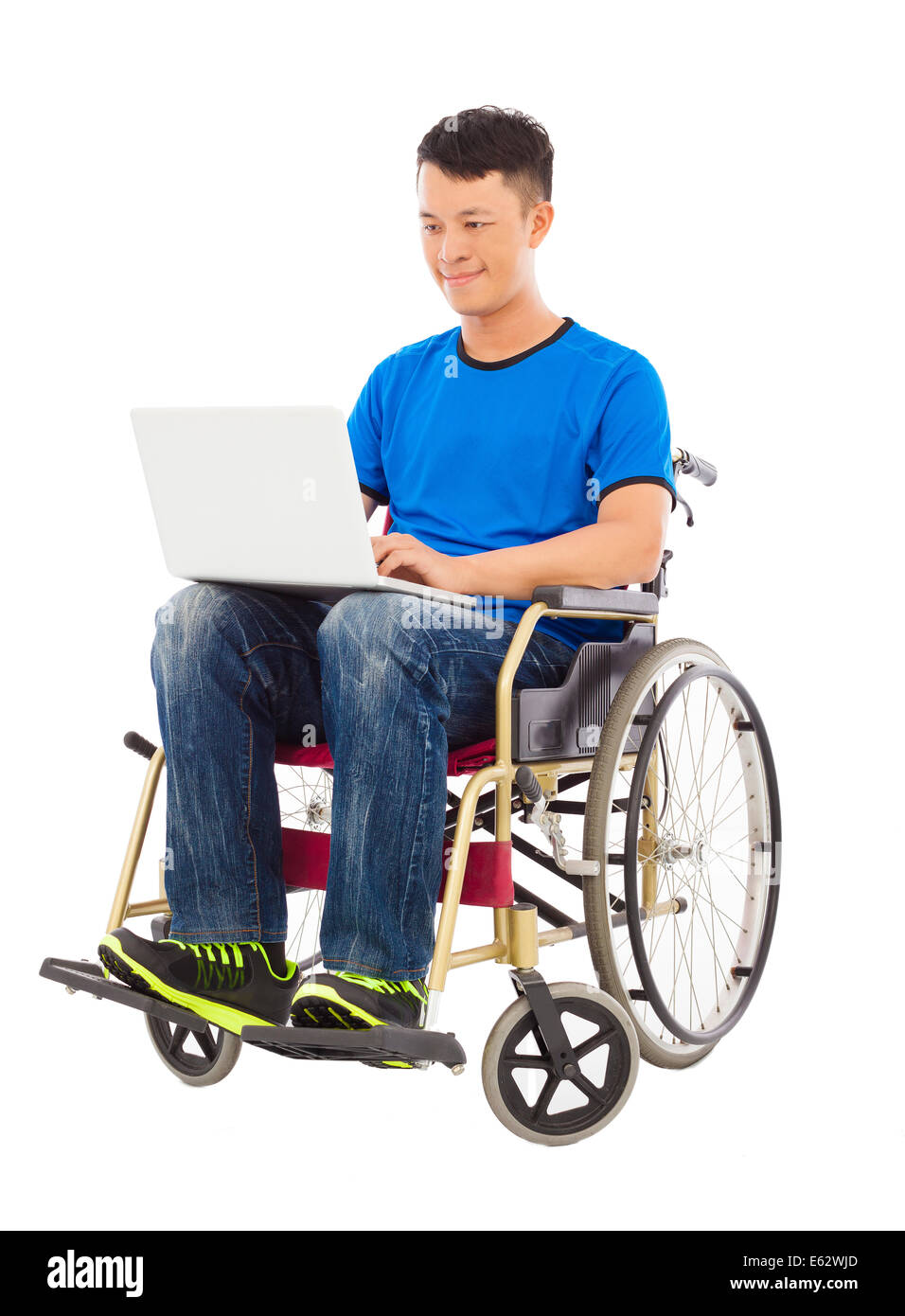 hoffnungsvoller junger Mann sitzt auf einem Rollstuhl mit einem laptop Stockfoto