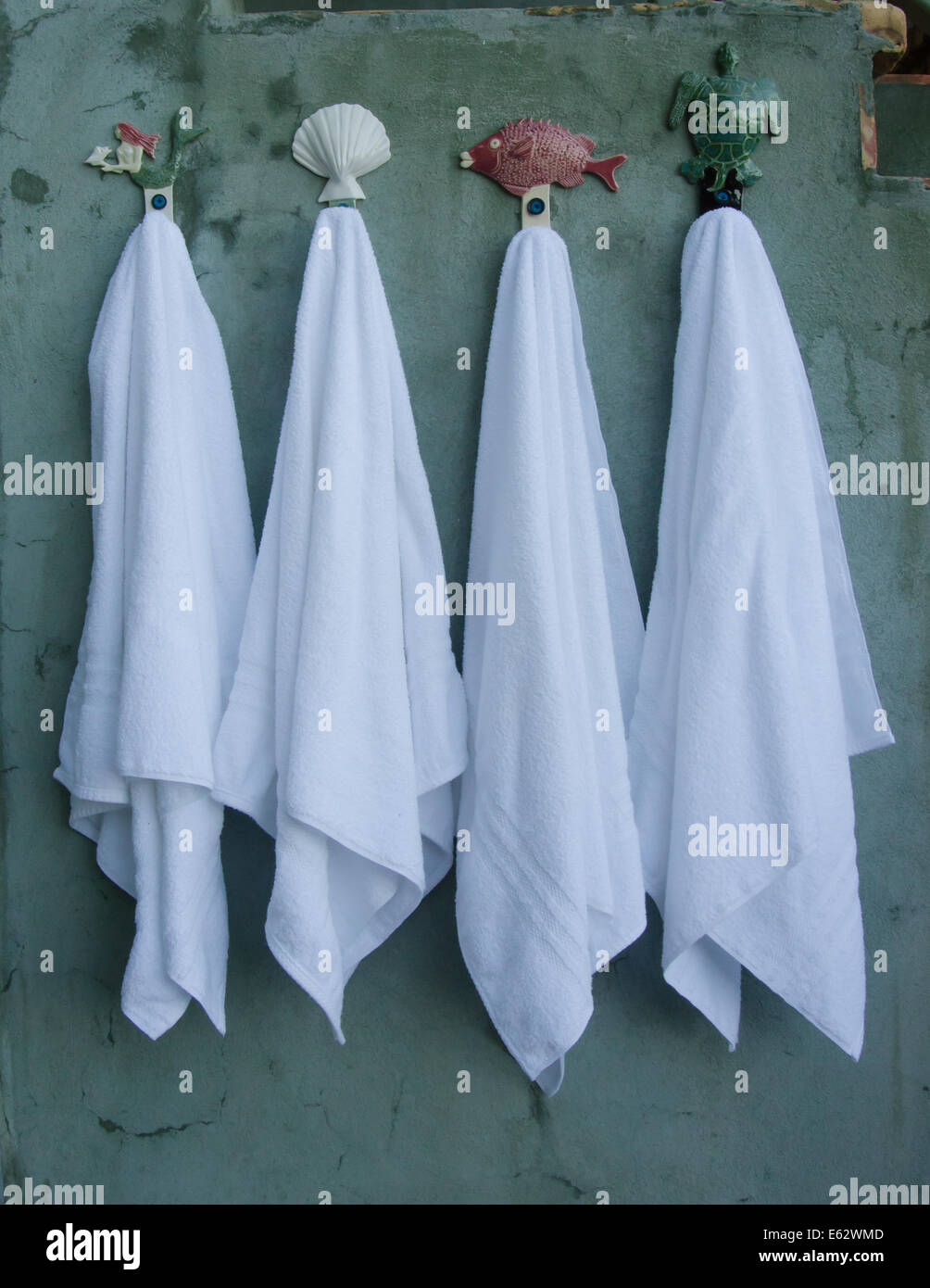 Vier knackige weiße Handtücher hängen am Strand unter dem Motto Haken in einem Gebiet, Außendusche Stockfoto