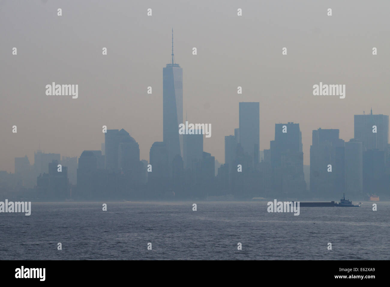 New York. Manhattan durch Nebel gesehen. Ein Welthandelszentrum Gebäude dominiert die Skyline. Ein Schlepper und ein Boot im Vordergrund. Stockfoto